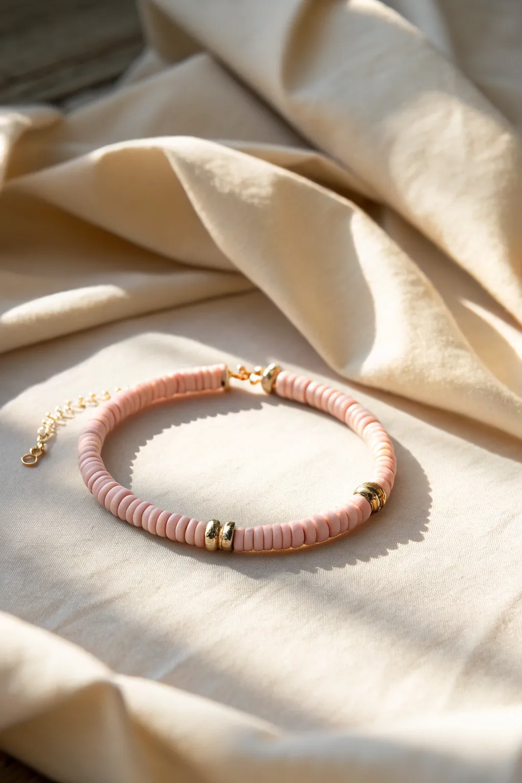 Monochrome heishi clay bead bracelet in blush tones on linen for a calm, minimalist look.