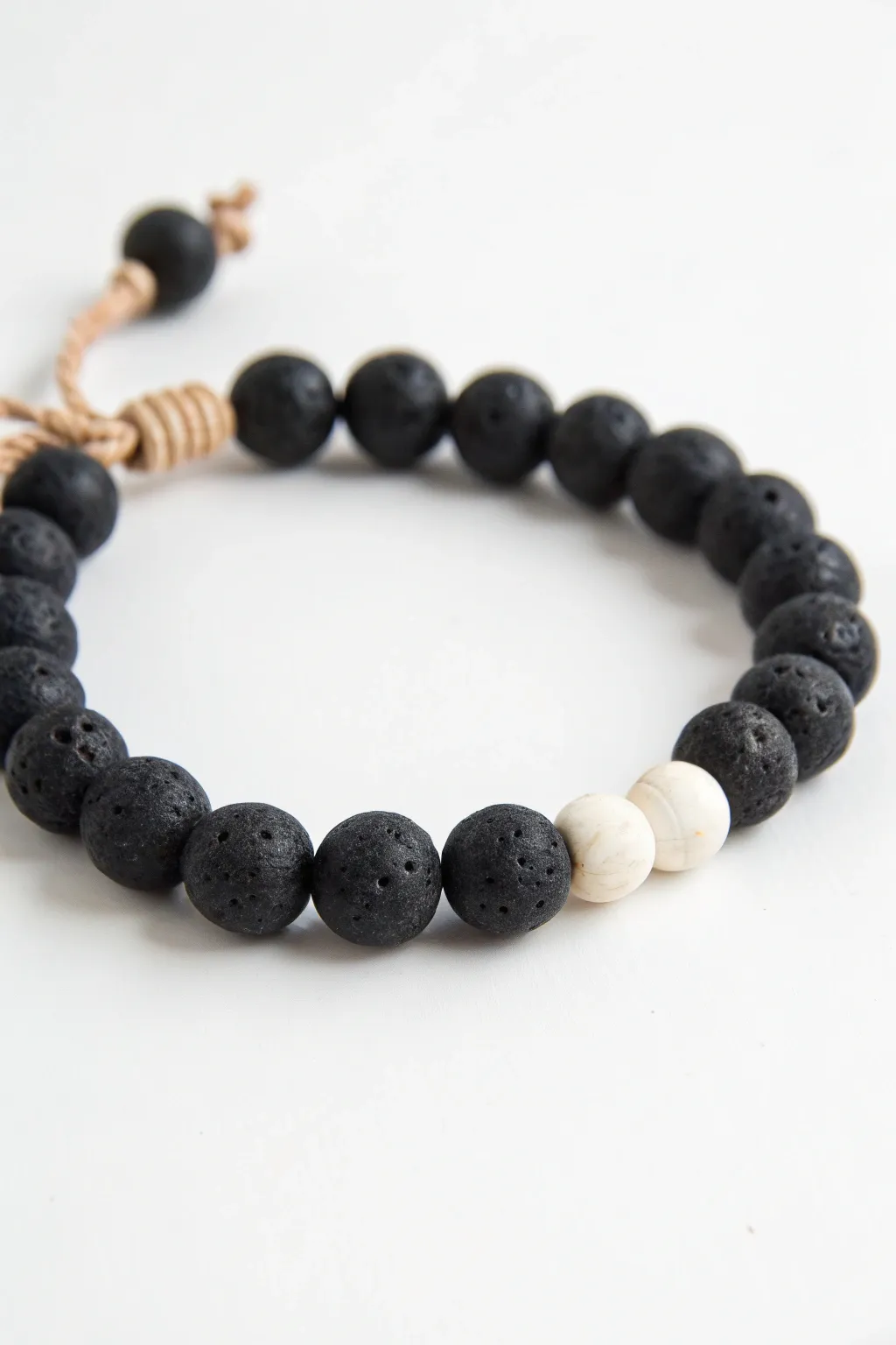 Mostly black clay bead bracelet with a crisp white pop near the knot, minimalist and bold.