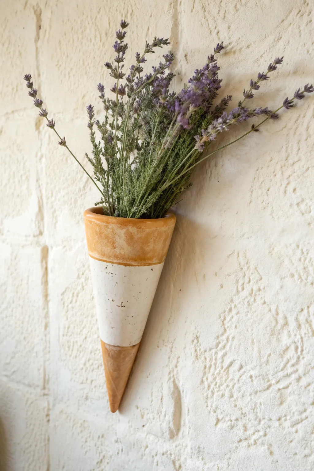 Tapered cone wall pocket in warm clay, a minimalist way to display lavender and eucalyptus.