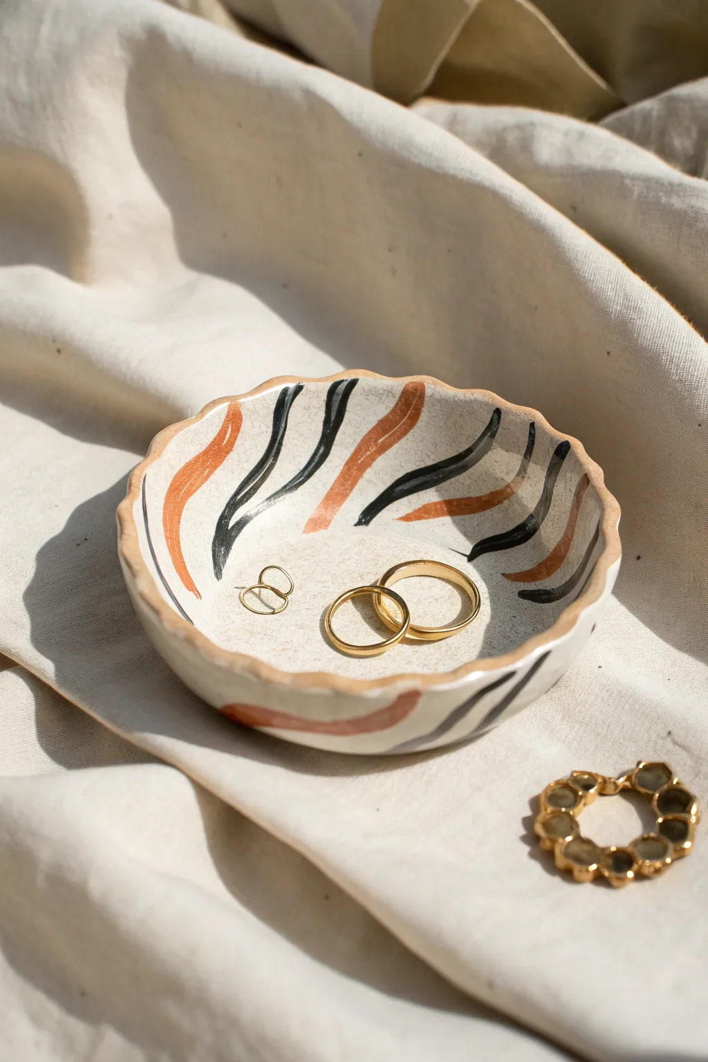 Bold-edged wavy trinket dish with graphic stripes, styled simply with rings and a hair clip.