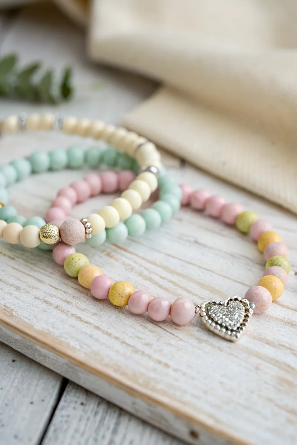 Soft pastel clay bead stack with a sweet heart charm for effortless, feminine bracelet layering.