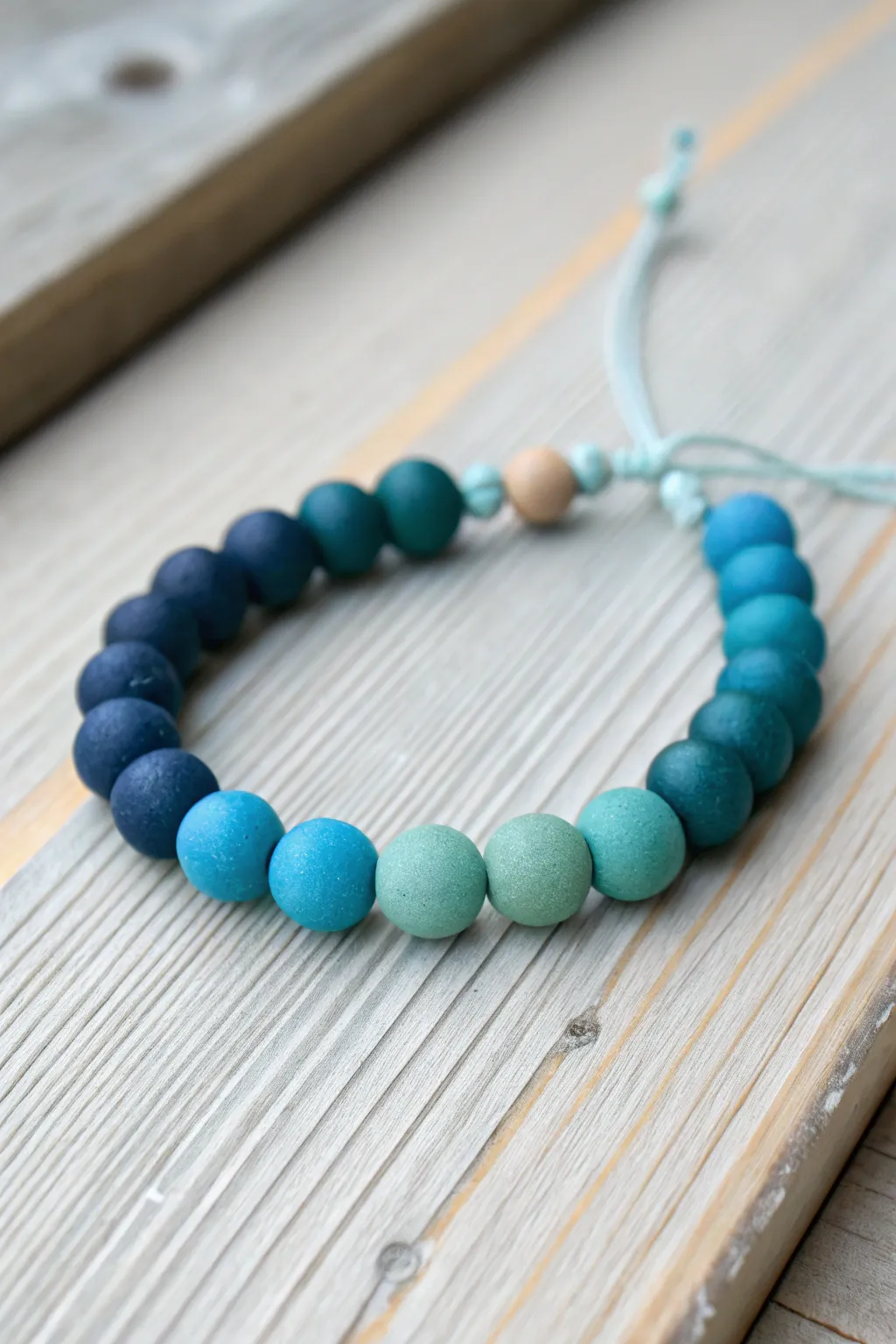 Ocean-blue clay bead bracelet gradient in navy, cobalt, aqua, and teal, styled minimal.