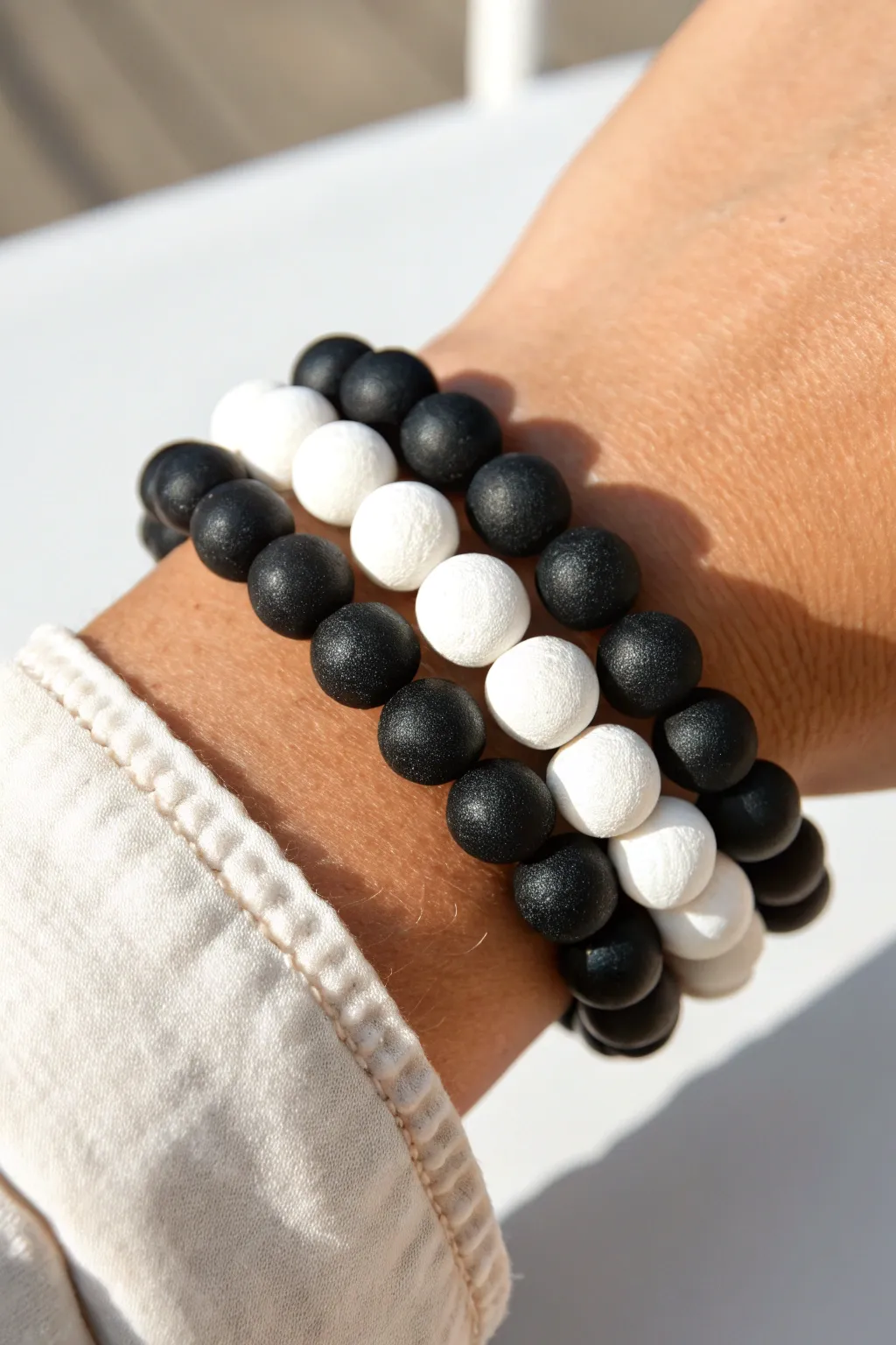 Classic black-and-white clay bead bracelets with minimalist pattern play and handmade texture.