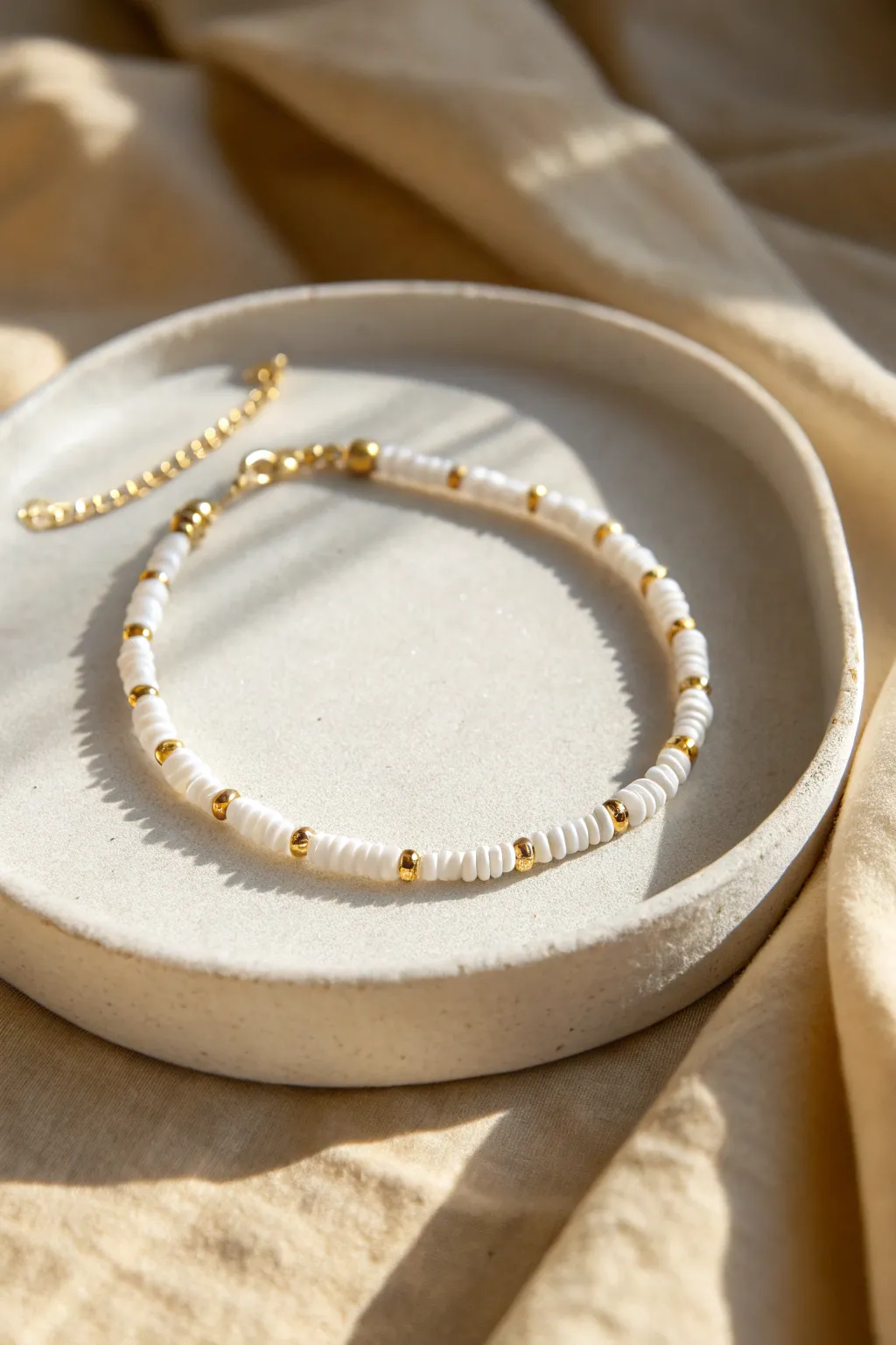 Crisp white heishi clay beads with rhythmic gold spacers for a minimalist, boho-luxe bracelet