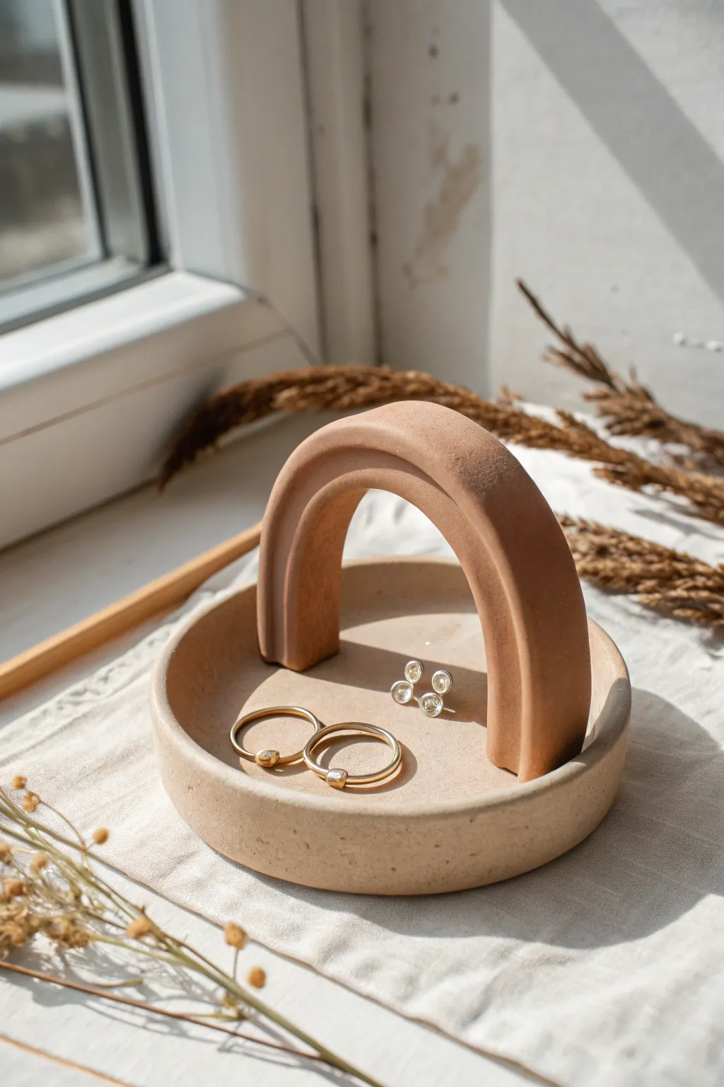 Minimal arch ring stand with dish base in earthy matte clay, styled for calm Scandinavian boho vibes