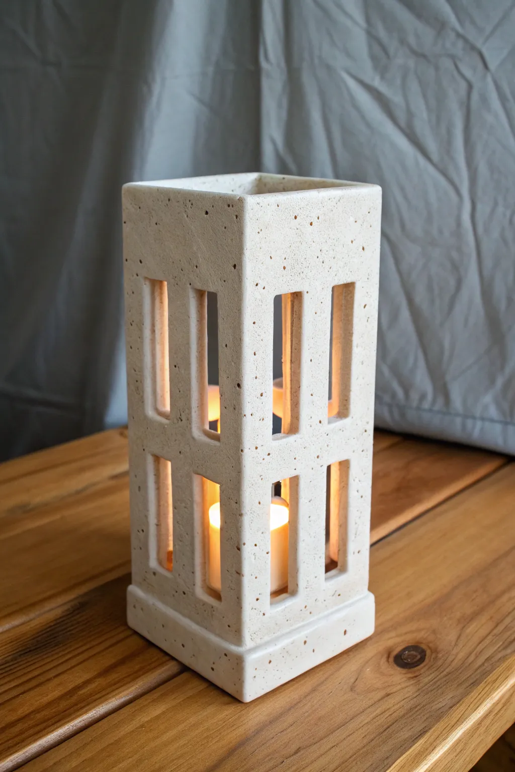 Minimal mitered-corner slab lantern with tiny cutouts, matte clay, and a gentle warm glow.