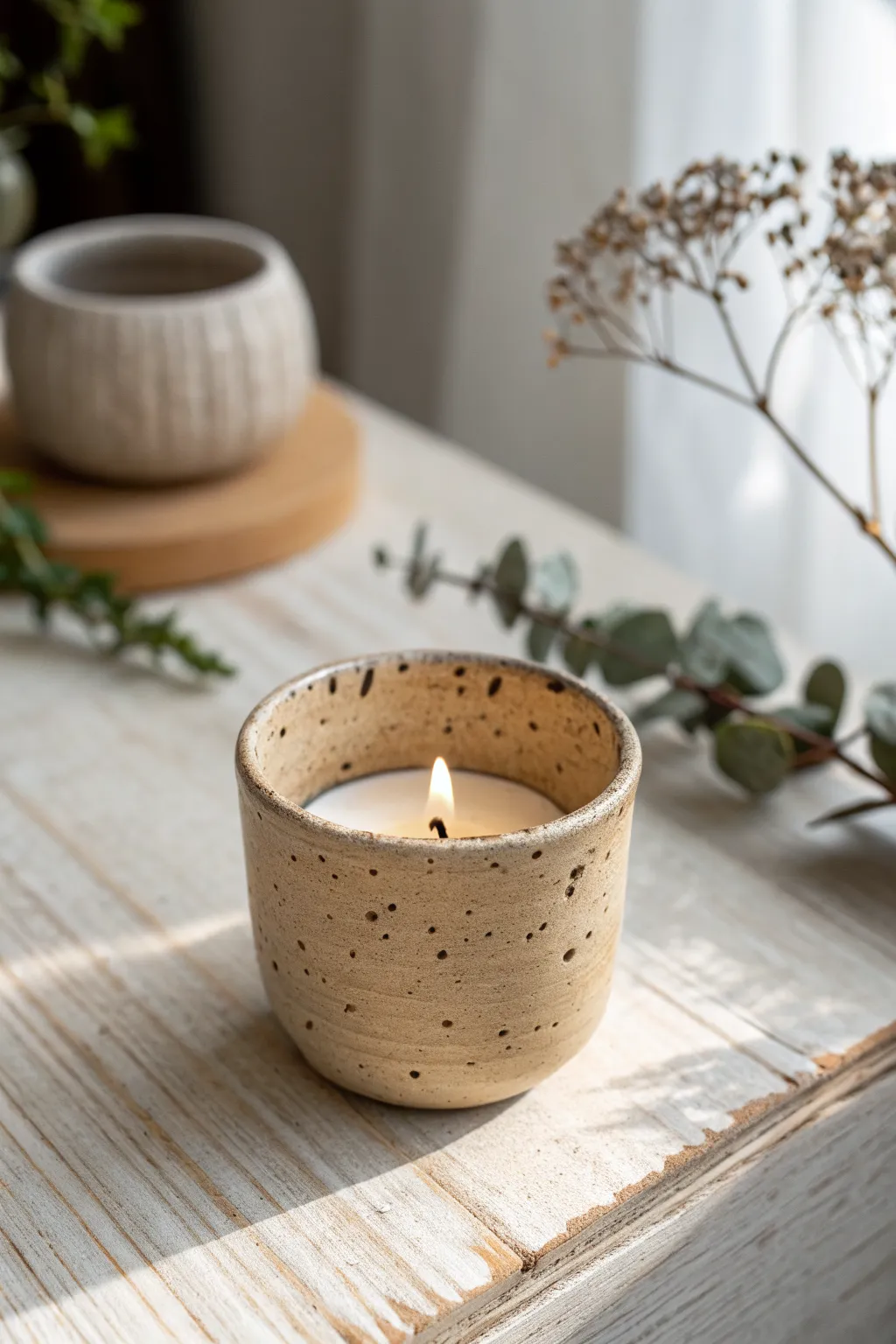 Speckled stoneware-look tea light cup on pale wood, minimalist boho decor with soft contrast