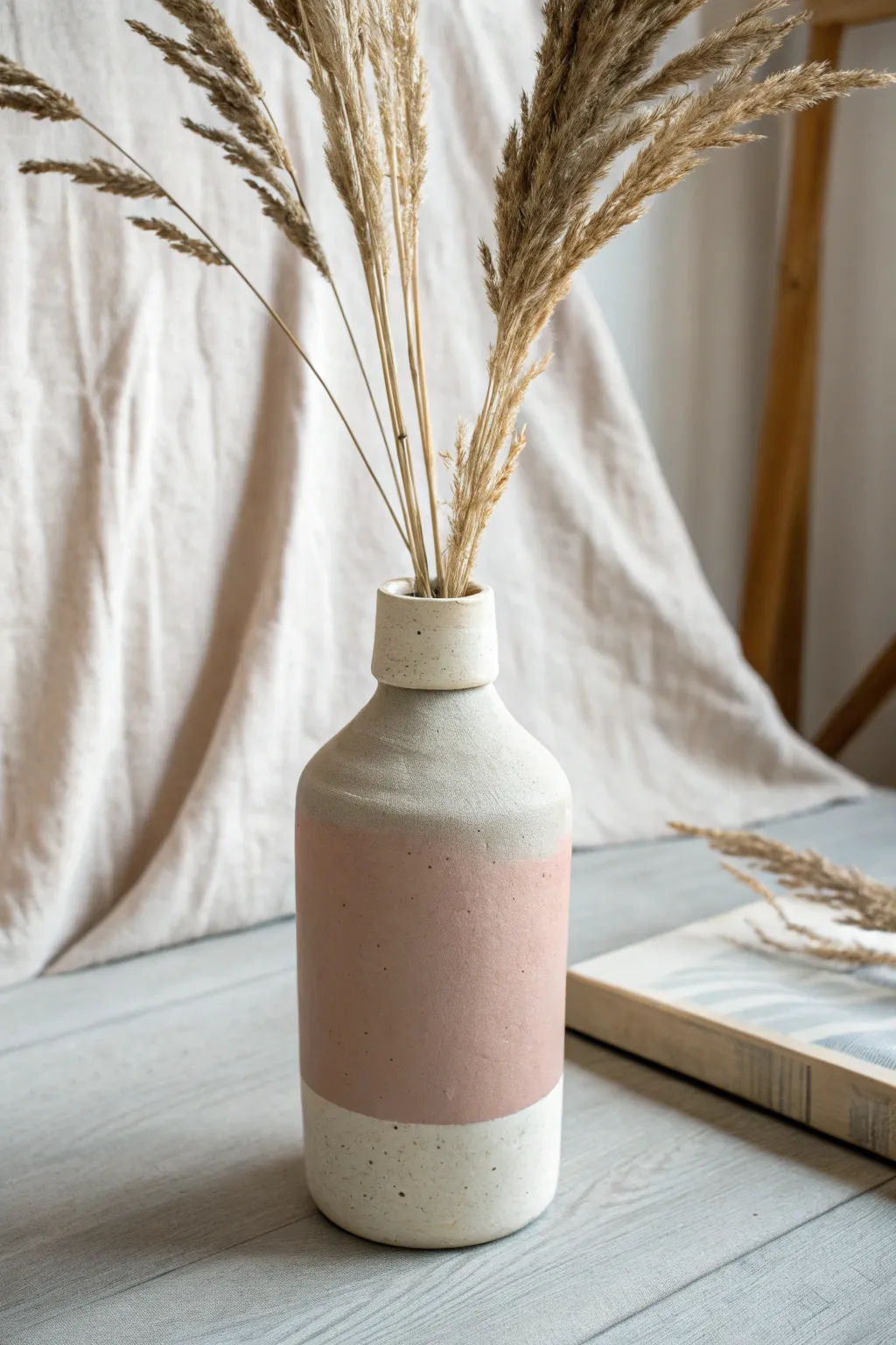 Easy bottle-sleeve clay vase cover in matte pastel with airy grasses, minimal and chic