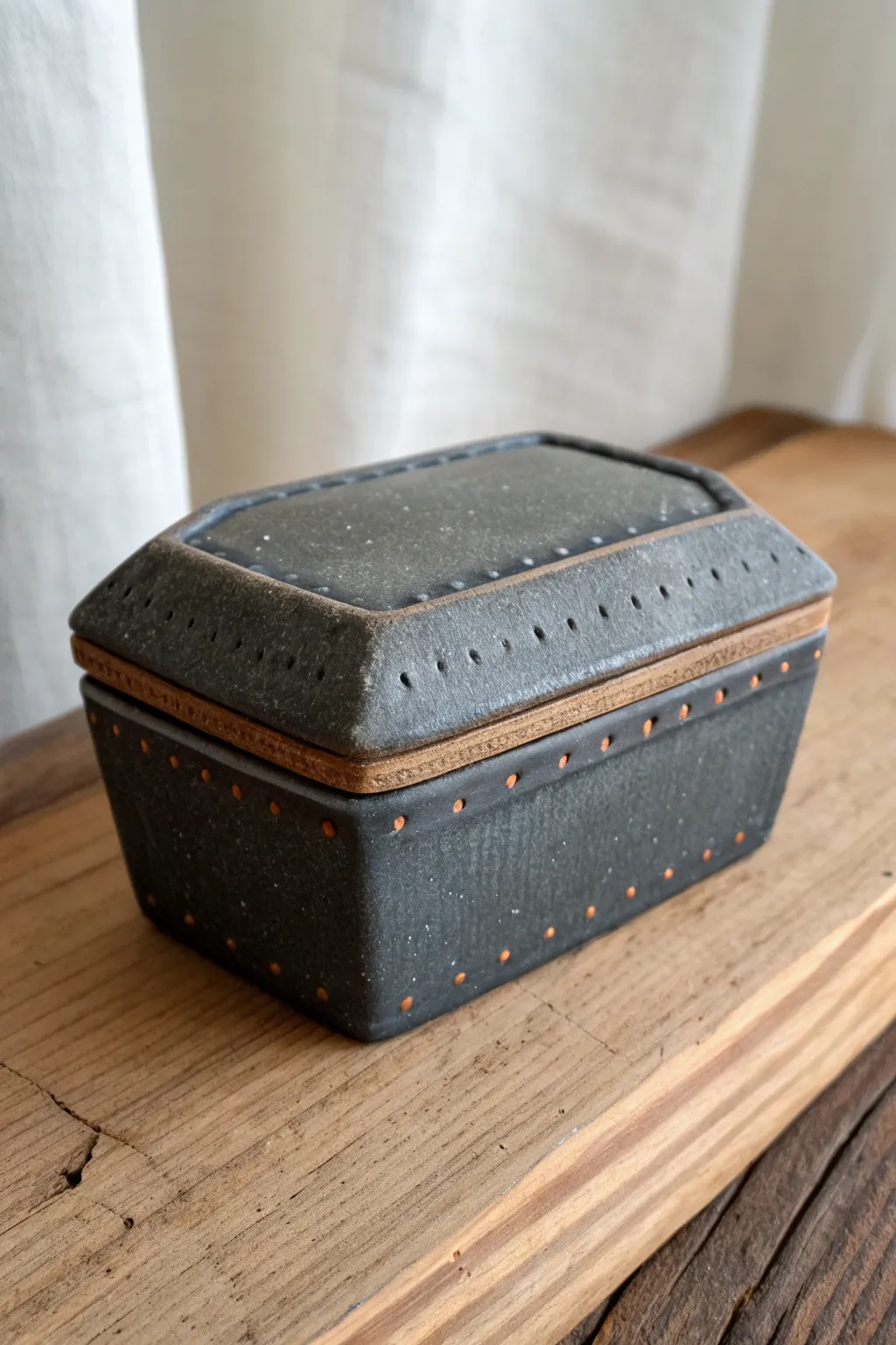 Haunted minimalism: coffin-shaped keepsake box in dark stone tones with simple rivet details.