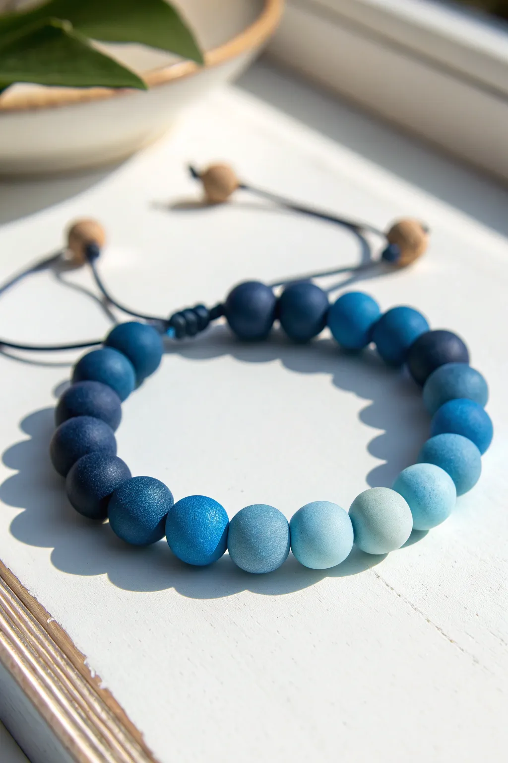 Minimal ombre clay bead bracelet in soothing blues, fading from navy to sky on clean white.