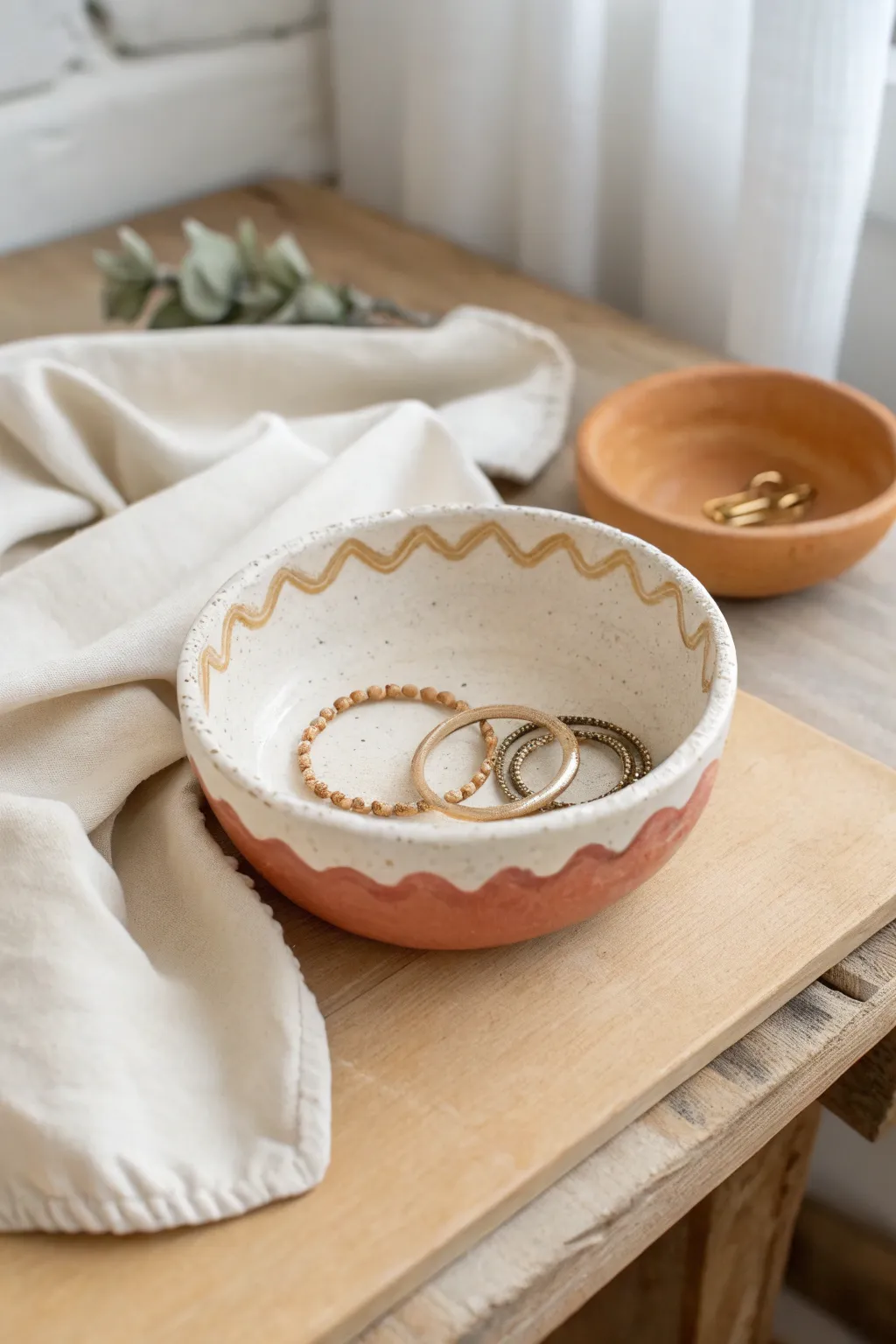 A simple wavy-rim jewelry bowl with a soft two-tone edge, styled for a calm adult vanity.