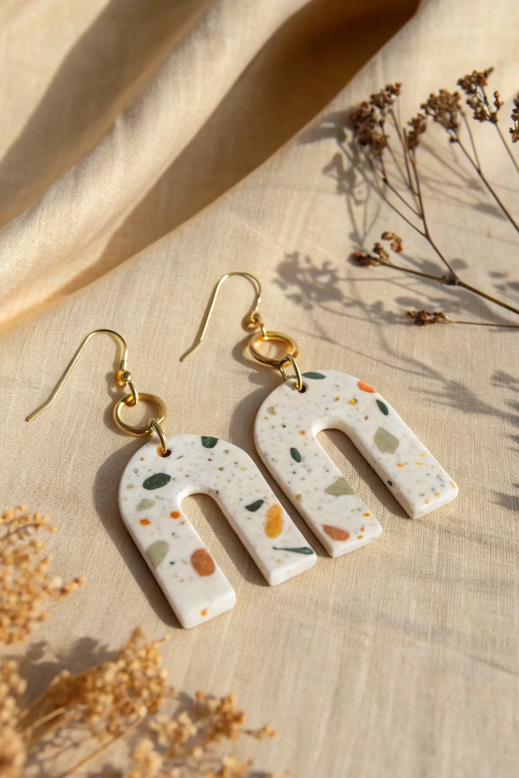 Minimal terrazzo epoxy clay earrings with soft earthy speckles, styled in clean Nordic light