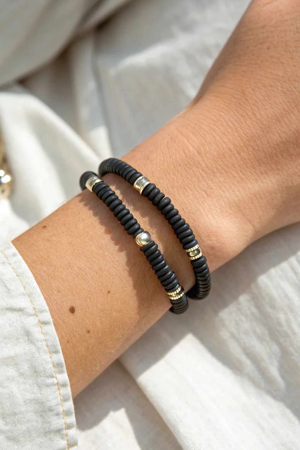 Black heishi bead bracelet with metallic spacers, minimal and bold with a subtle shine.
