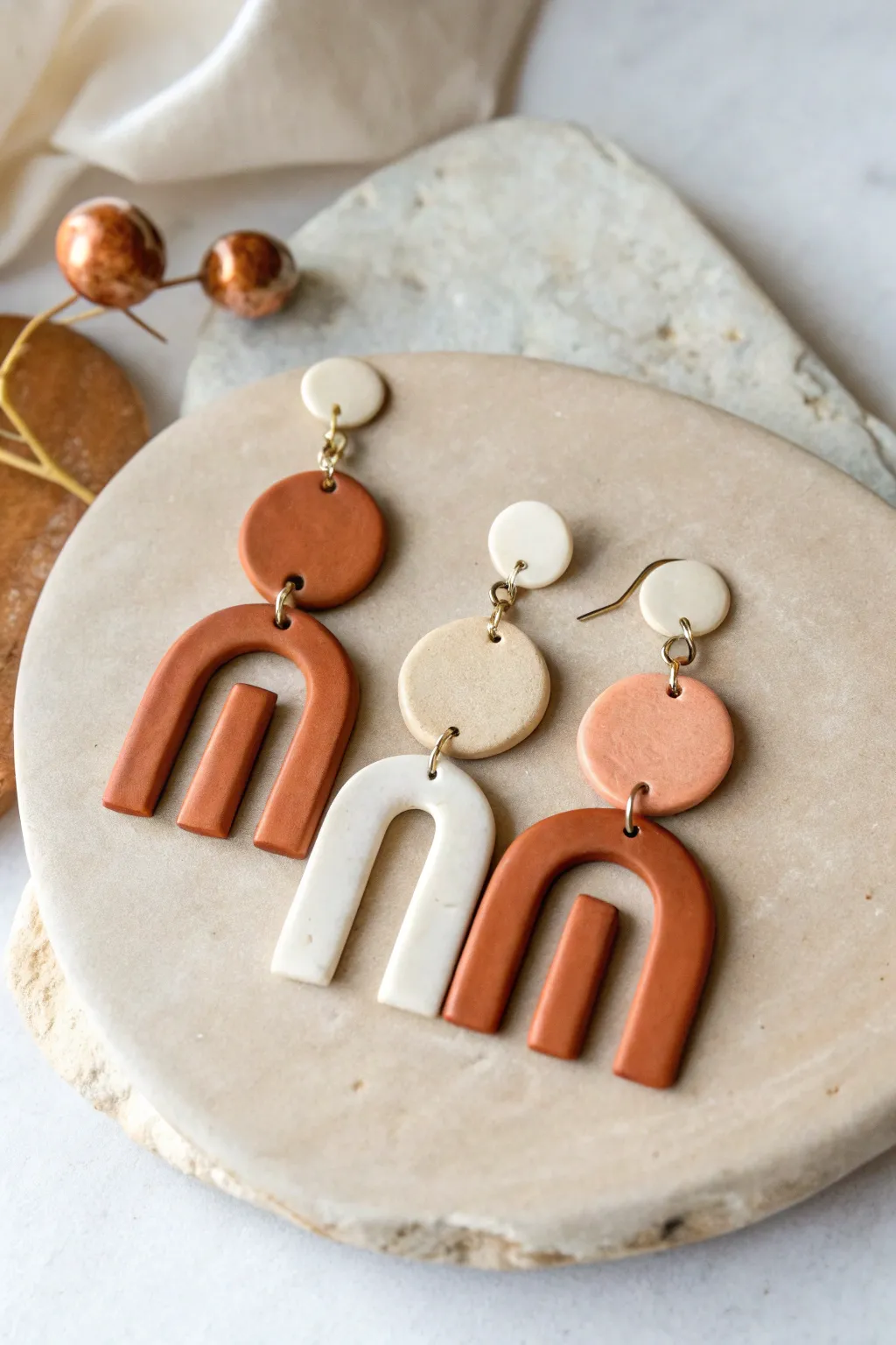 Minimalist flat clay geometric earrings in matte neutrals, styled symmetrically with crisp contrast.