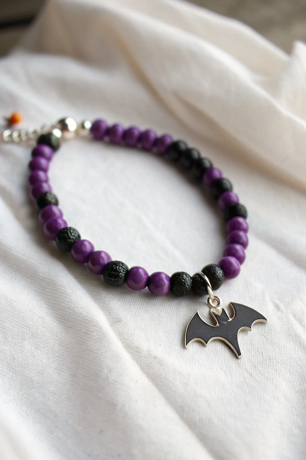 Deep purple and black clay bead bracelet with a tiny bat charm for minimalist Halloween vibes
