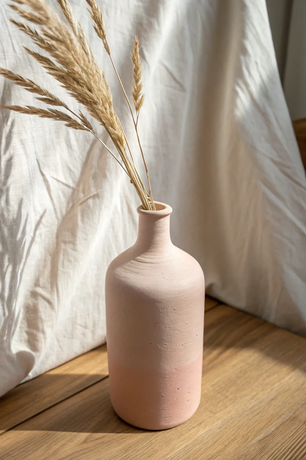 Clay-covered bottle vase in dusty blush with pampas grass, minimalist boho decor idea