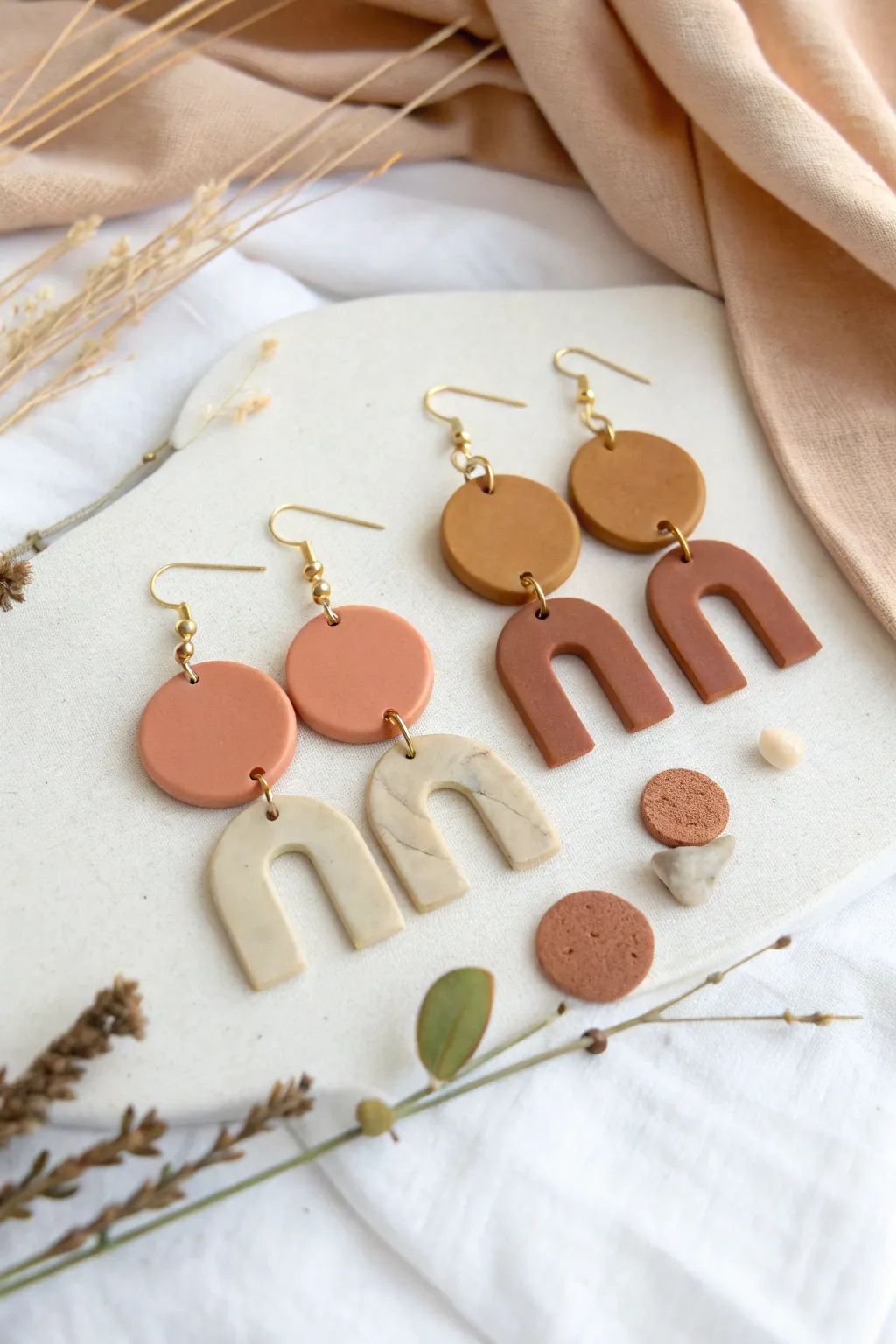 Minimal polymer clay statement earrings in warm neutrals, styled simply on a bright white backdrop