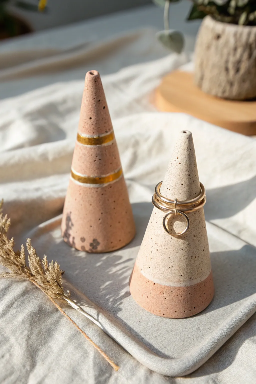 His-and-hers ring cones in neutral clay with soft stripes, simple, modern, and handmade