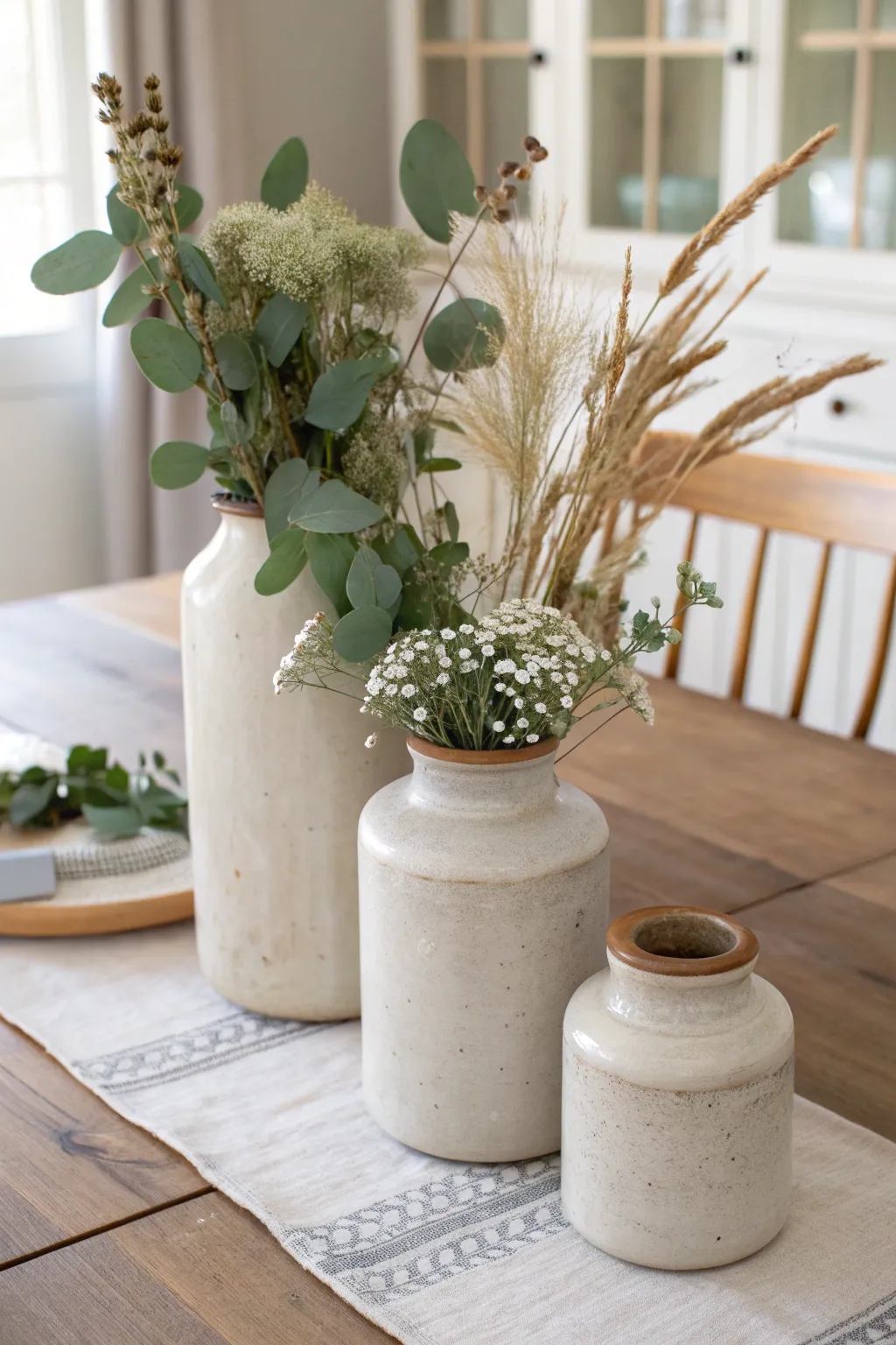 Mixed-size vintage crocks create a calm, Scandinavian-inspired centerpiece with greenery and blooms