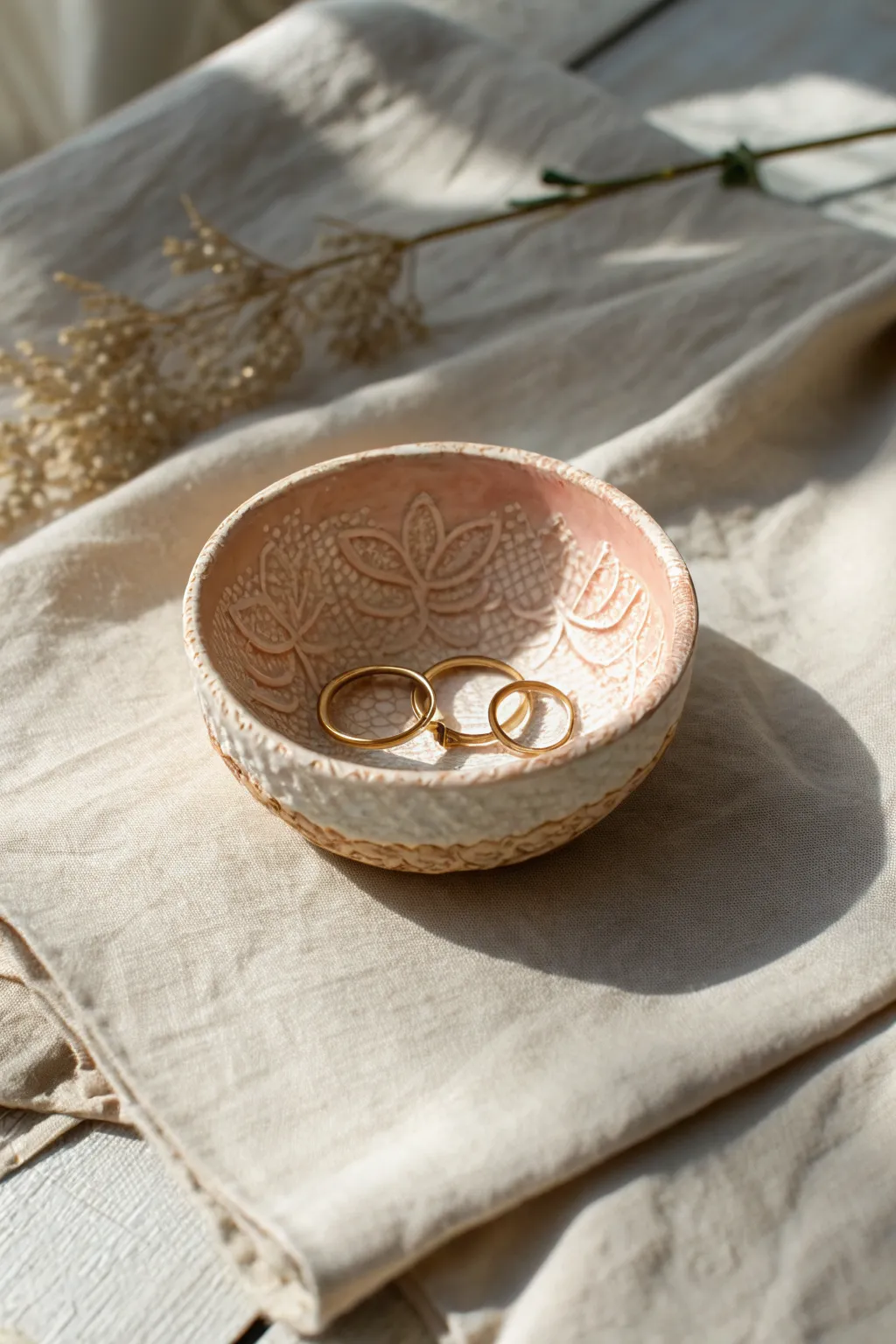 Lace-textured polymer clay bowl on linen, styled with delicate earrings for a vintage touch.