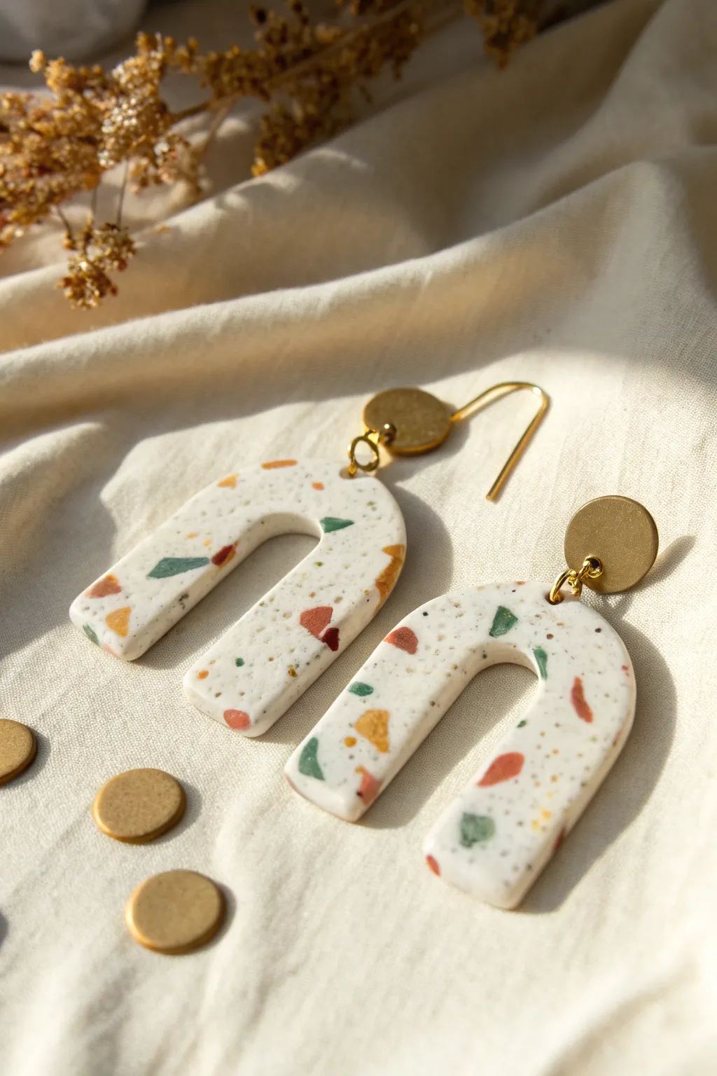 Terrazzo speckle polymer clay earrings in soft neutral tones, minimal flat lay with boho warmth