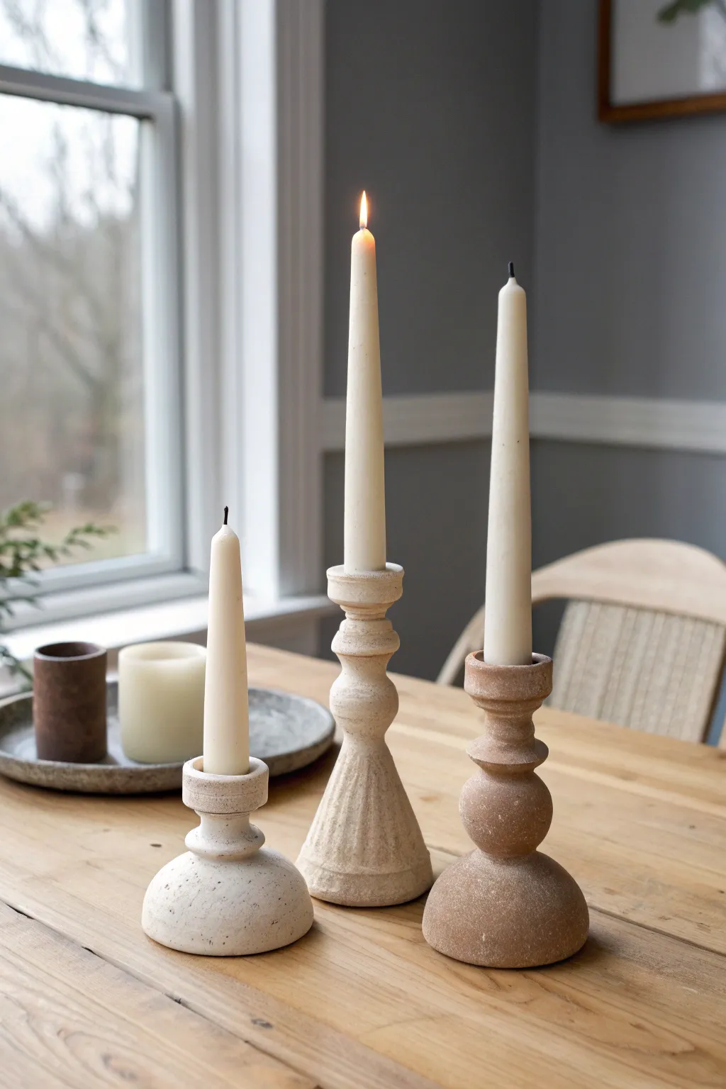 Minimal chunky clay taper holders in neutral tones, softly lit for a calm Scandinavian mood