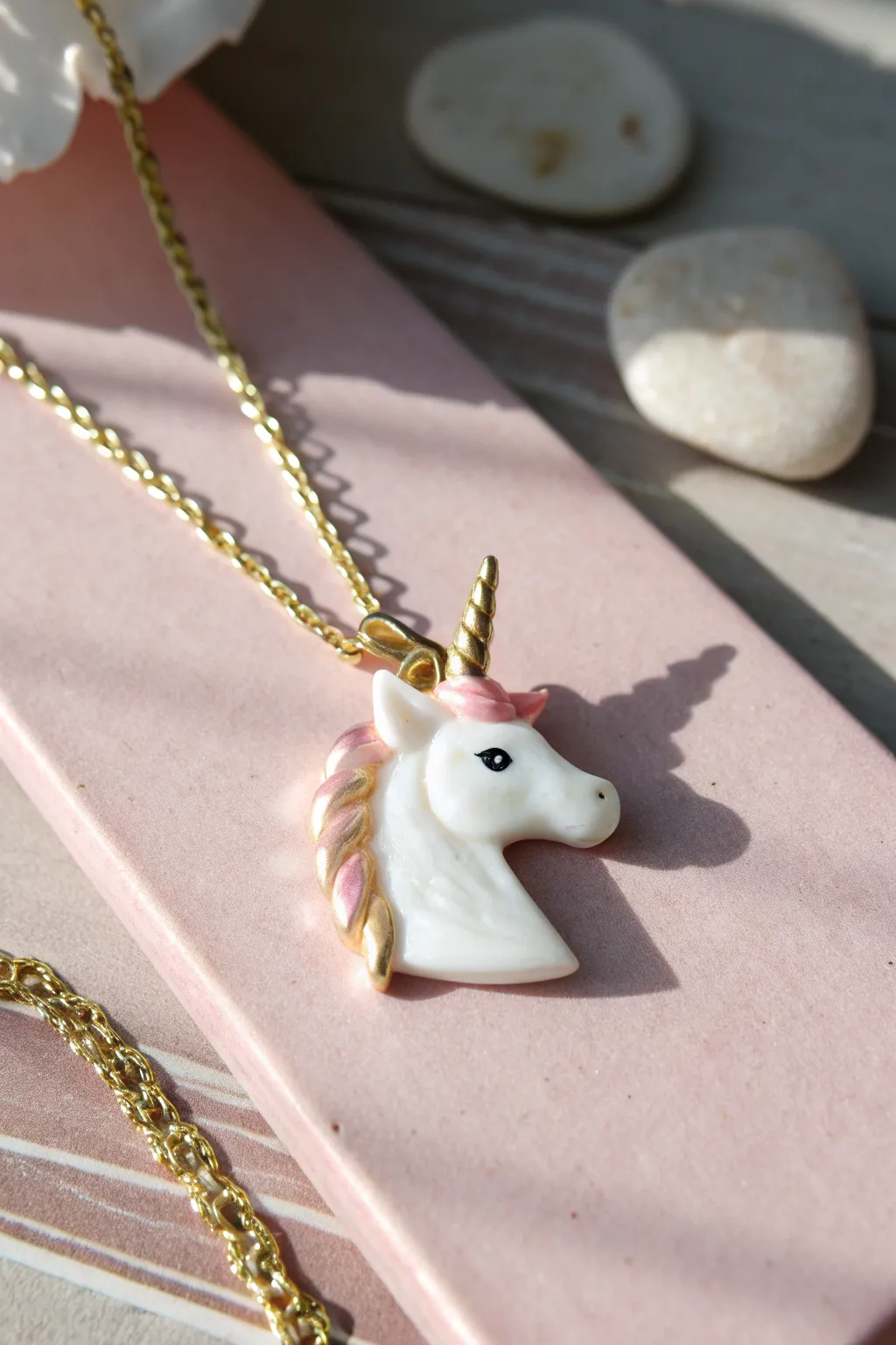 Glossy clay unicorn pendant with petite horn, styled on blush pastel for dreamy minimal decor