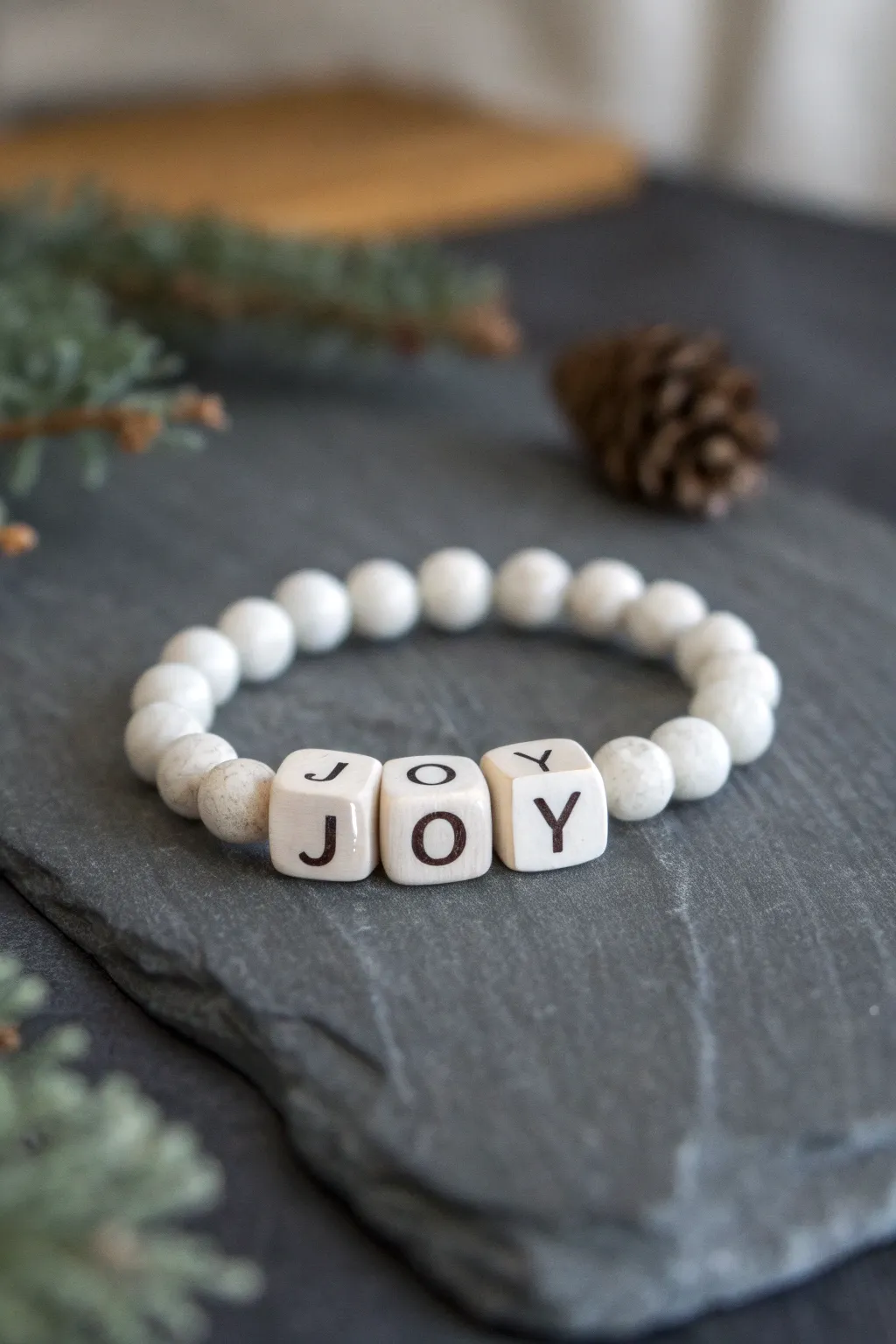 Minimal winter clay bead bracelet with JOY letter beads, photographed in cozy Scandinavian contrast.