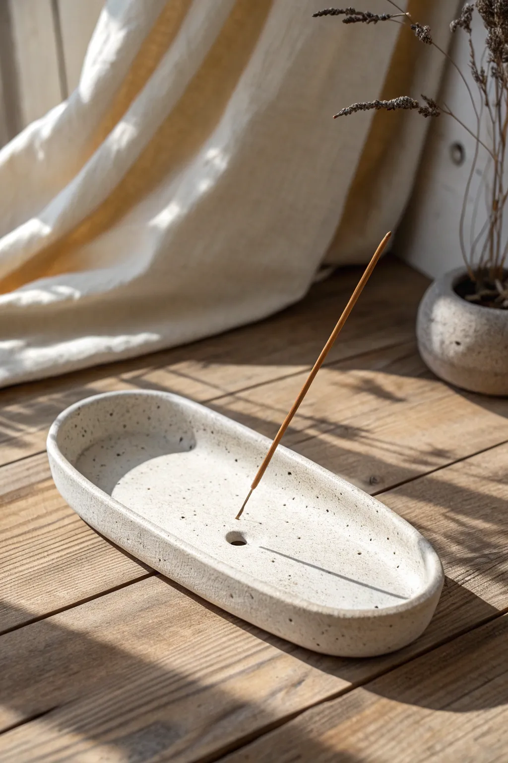 Minimal speckled air dry clay incense holder with a calm linen backdrop and soft natural light