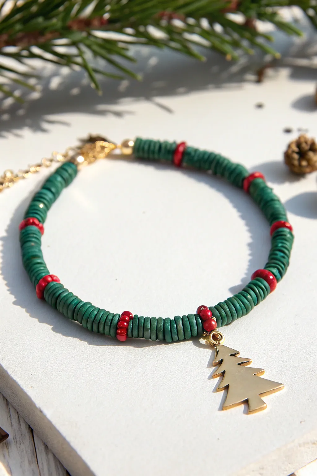 Mini Christmas tree charm bracelet in green heishi beads with red pops, simple and festive.
