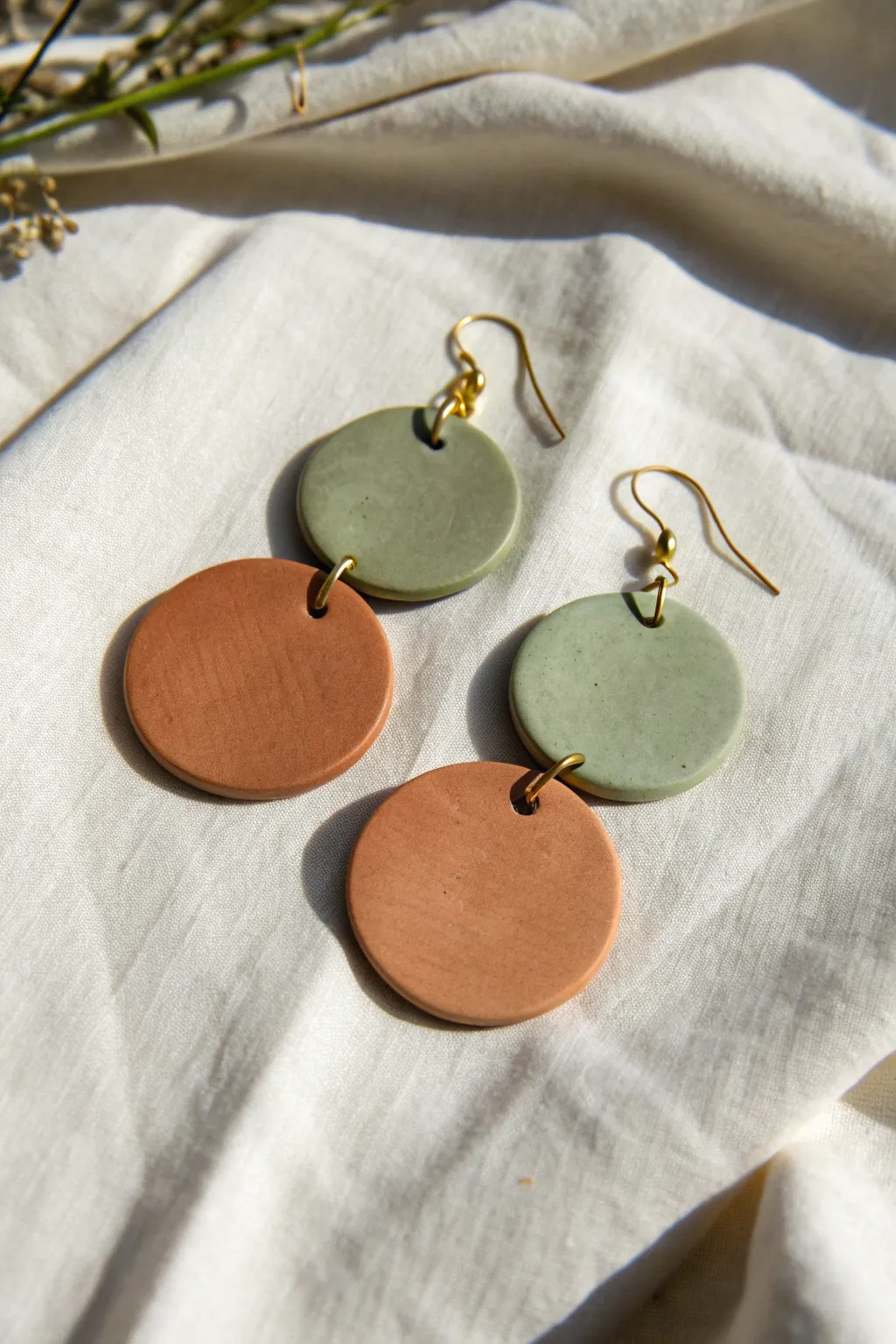 Minimalist layered clay circle dangle earring in earthy tones on a soft neutral backdrop.
