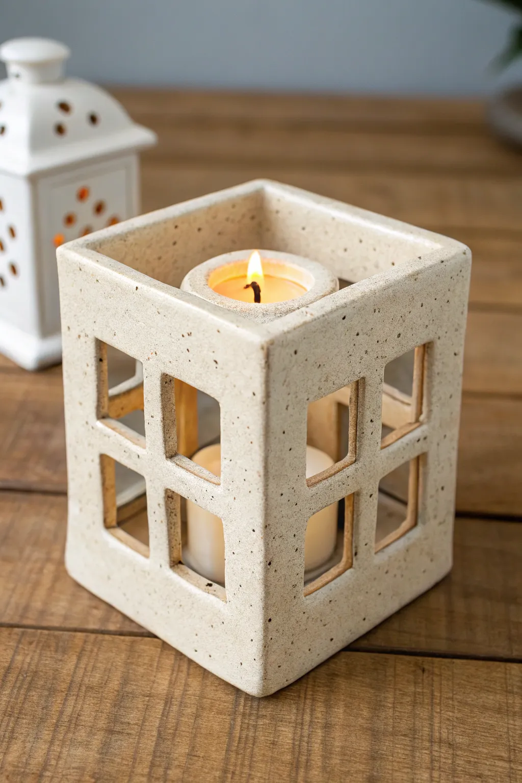 Simple slab-built tea light lantern with clean cutout windows, glowing softly on a calm backdrop.