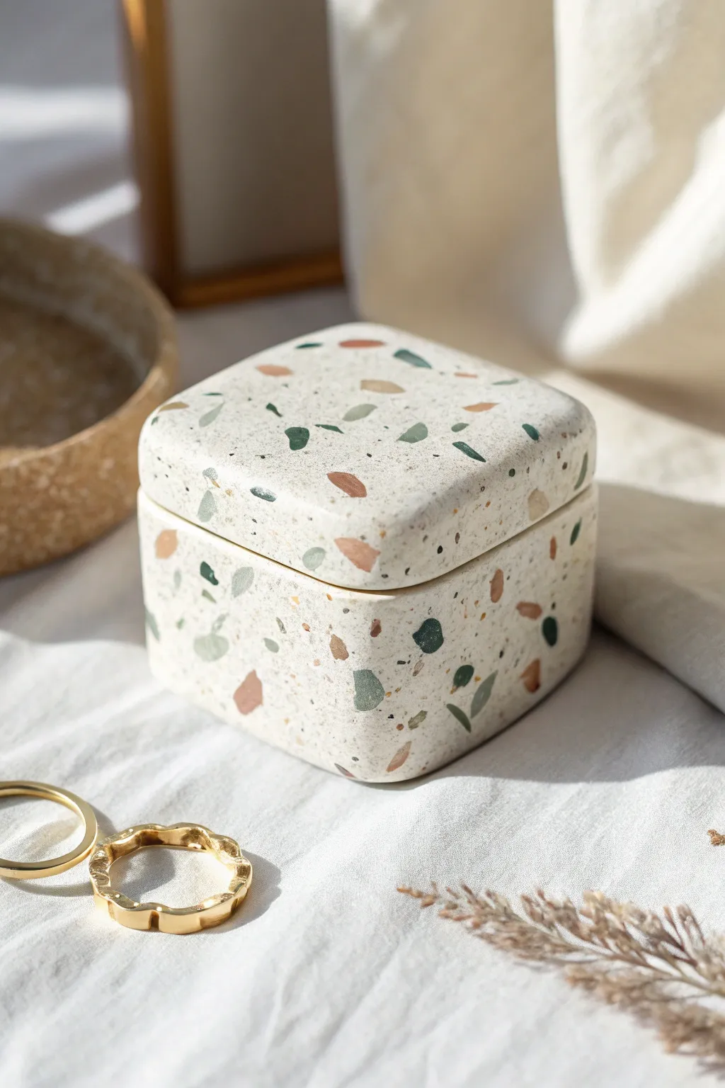 Minimal terrazzo speckle polymer clay jewelry box with soft pastel flecks and tiny rings nearby.