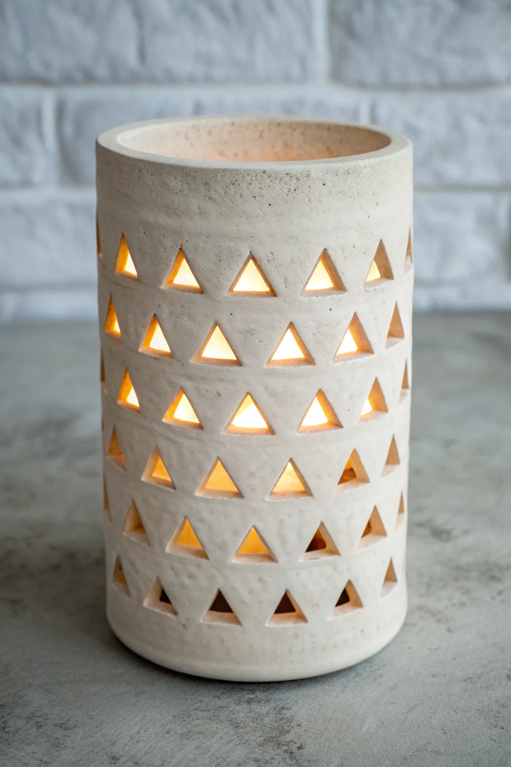 Minimal clay lantern with triangle cutouts, glowing warmly for a clean Scandinavian graphic look