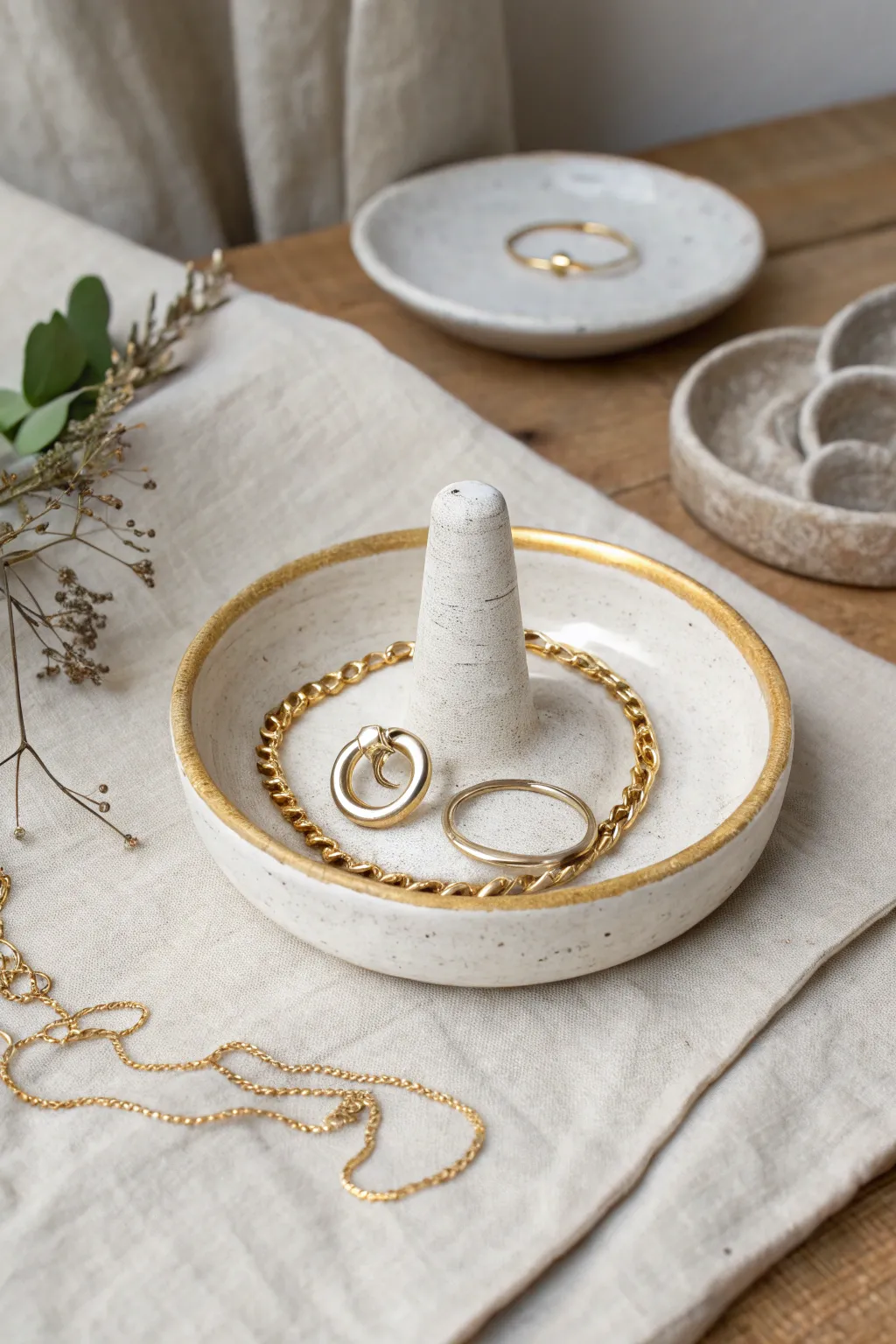 Simple clay ring holder with gold trim, styled with rings and a delicate necklace for boho minimal charm.