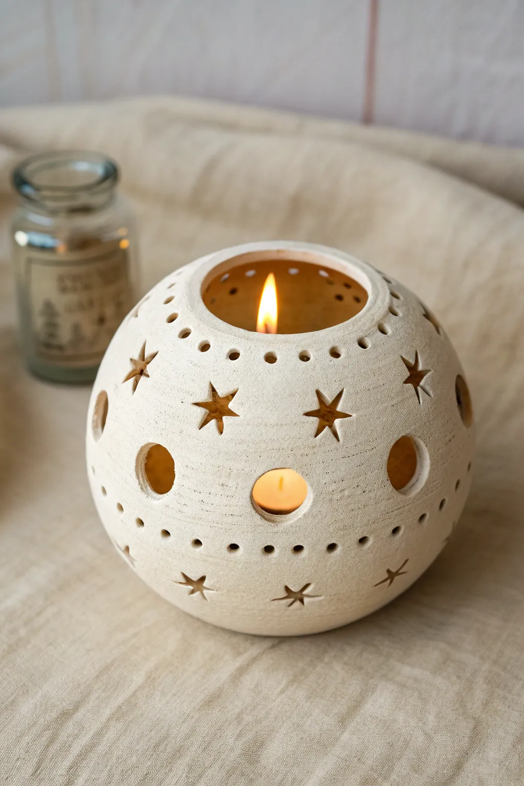 Minimal pierced clay sphere lantern with a soft tea light glow, simple Scandinavian boho charm.