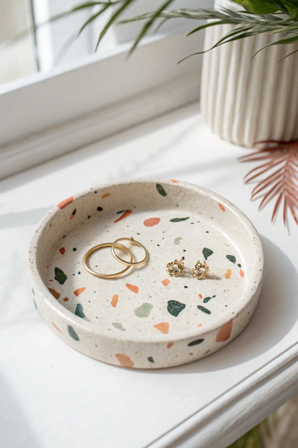 Terrazzo-speckled clay trinket dish with hoops and charm, minimal boho styling on white.