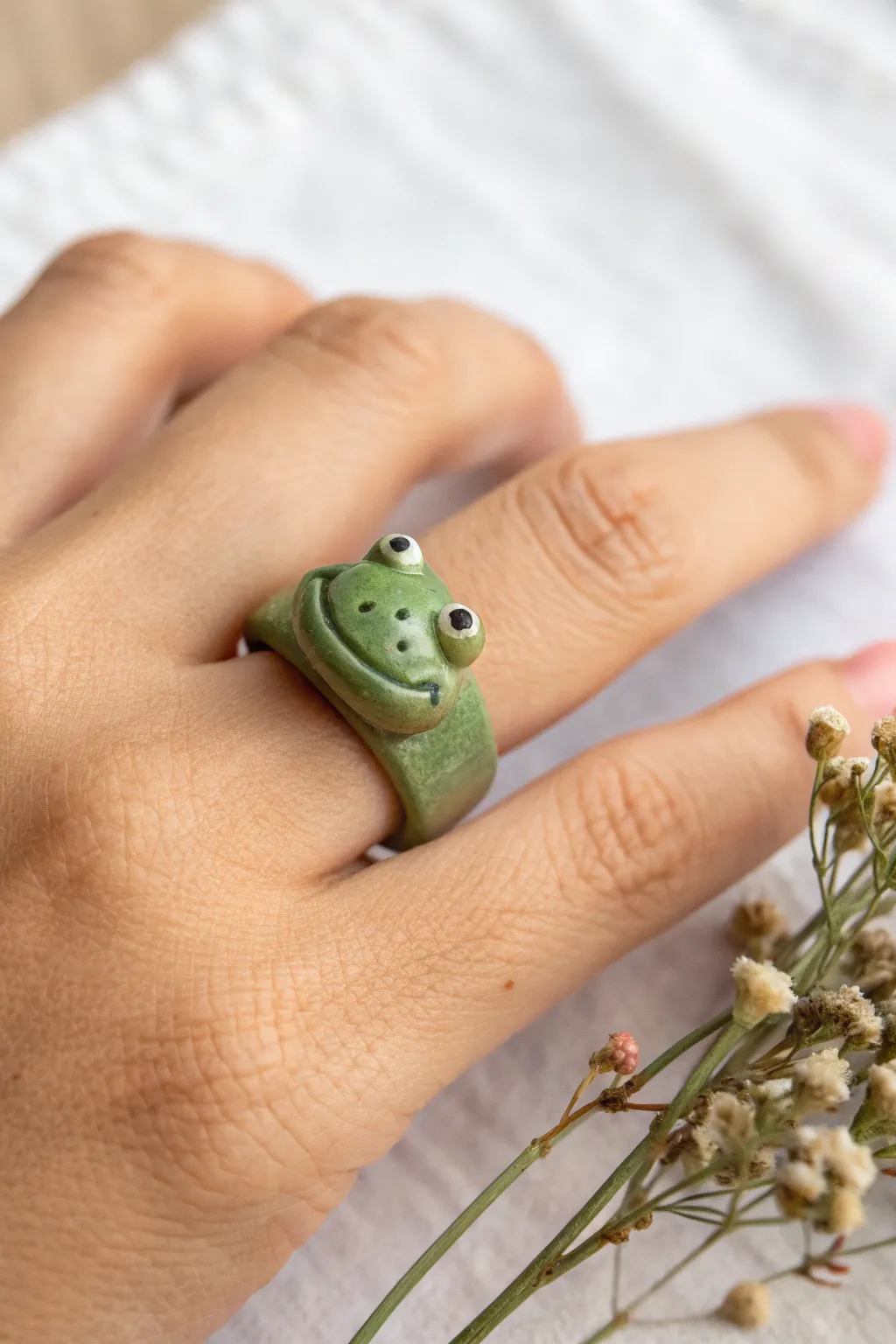 Handmade green frog face band ring on finger, minimalist cute clay ring inspo with boho charm.
