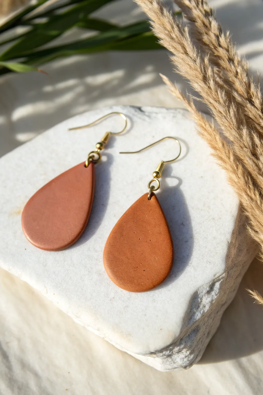 Minimalist teardrop polymer clay earring in earthy satin finish with simple scale reference