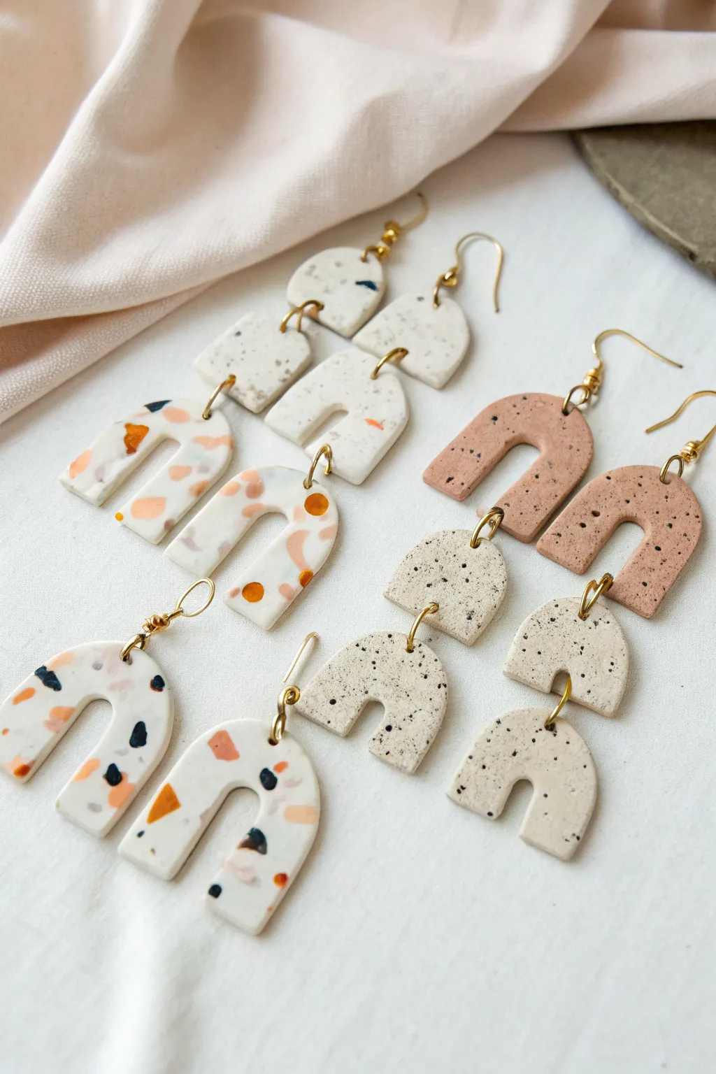 Terrazzo speckle slab earrings in simple shapes, styled minimally on linen with crisp contrast.
