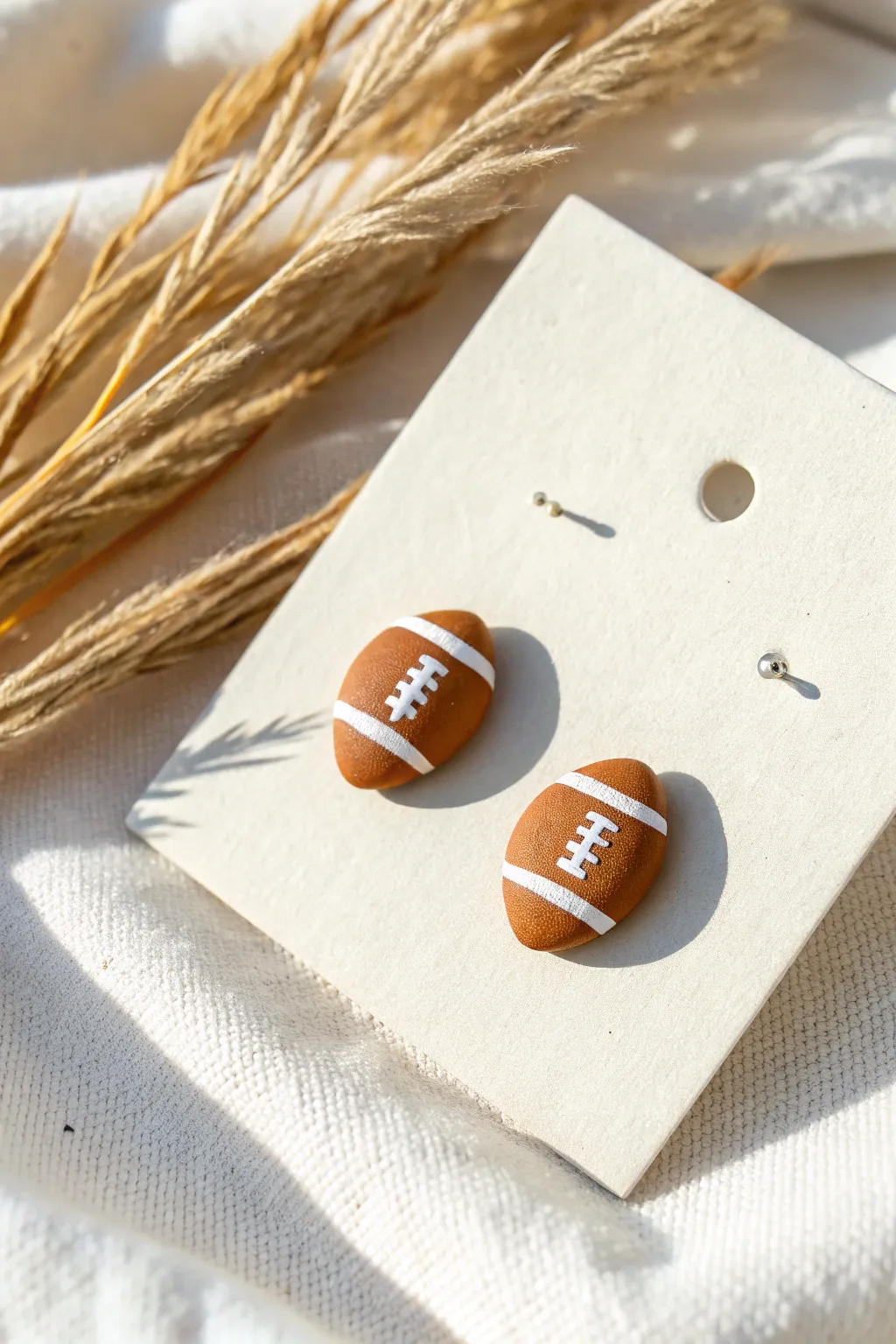Minimalist handmade football stud earrings in clay, clean and cute with crisp lace detail.