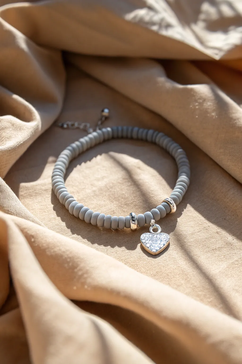 Matte grey heishi beads paired with a tiny heart charm for a soft minimalist statement