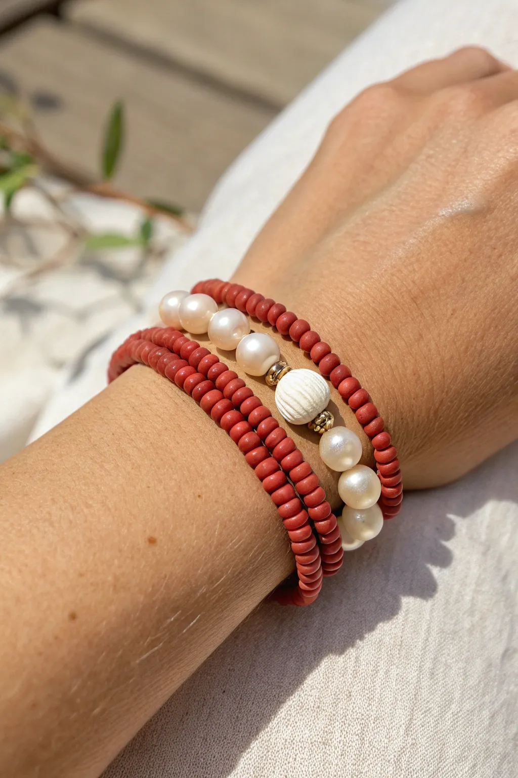 Matte red clay heishi meets luminous pearls for a minimalist boho stack with bold contrast.