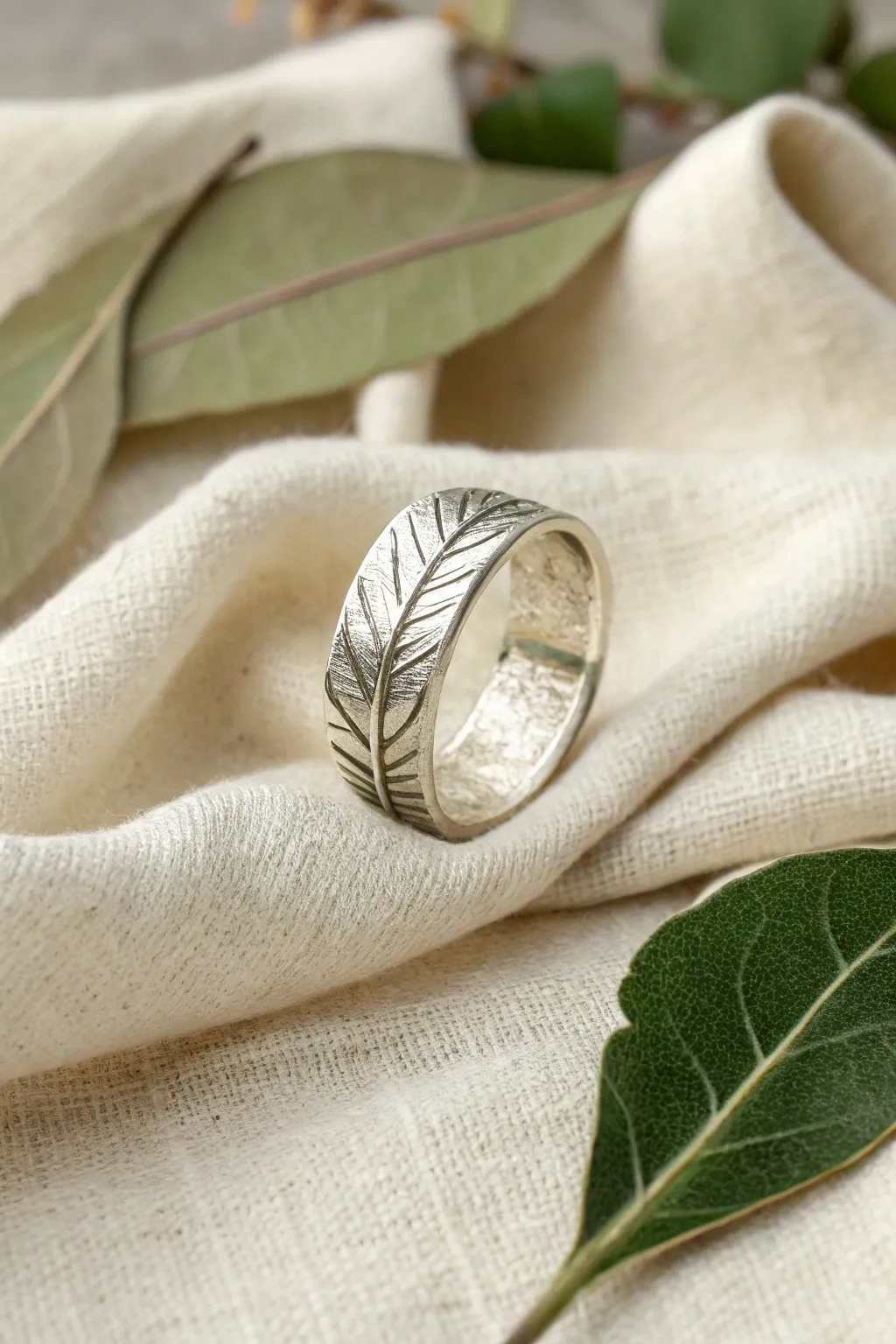 Leaf-impressed silver clay ring with organic veins, styled on linen with a fresh leaf.