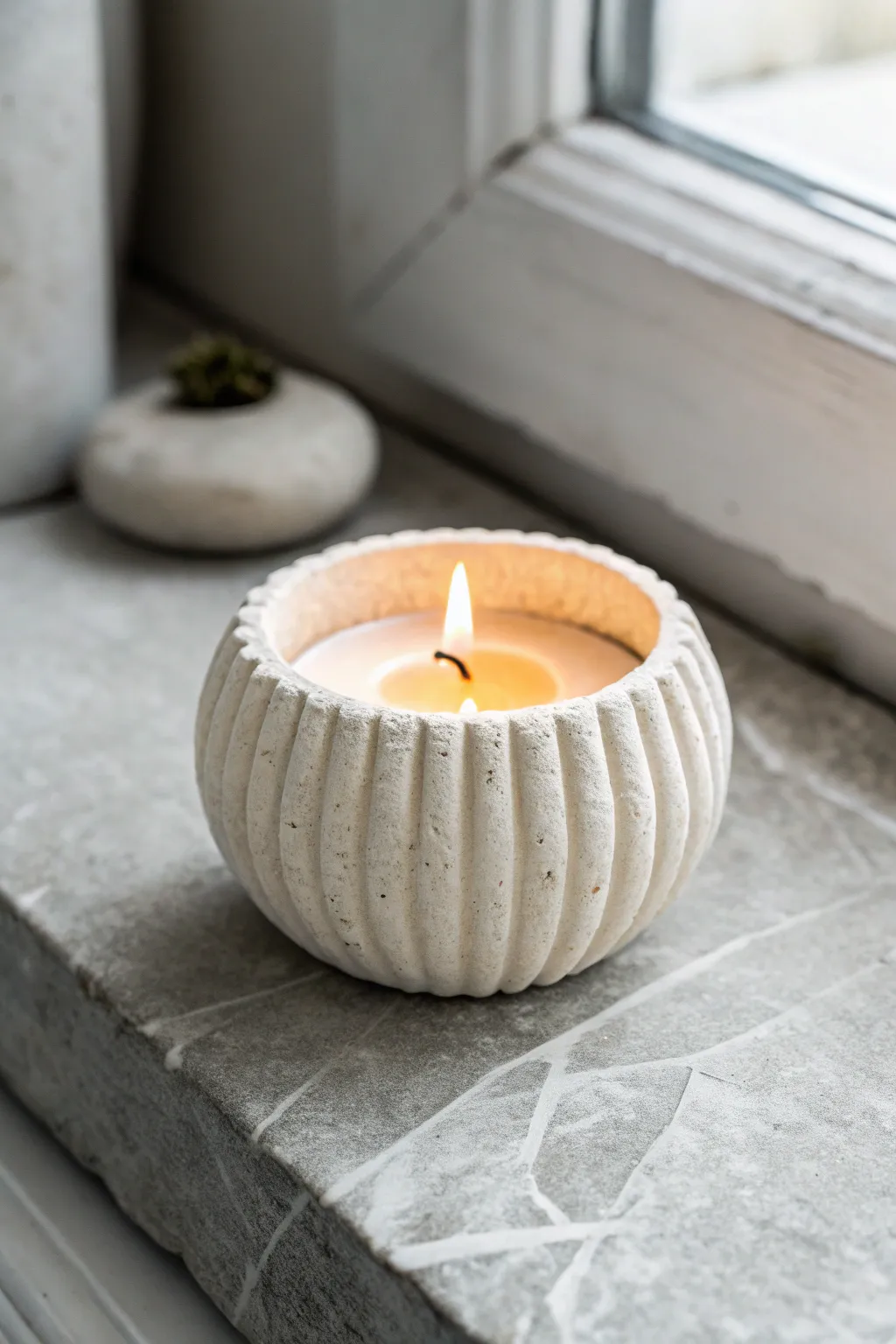 Creamy white fluted clay tea light holder on stone, softly lit for cozy minimalist vibes