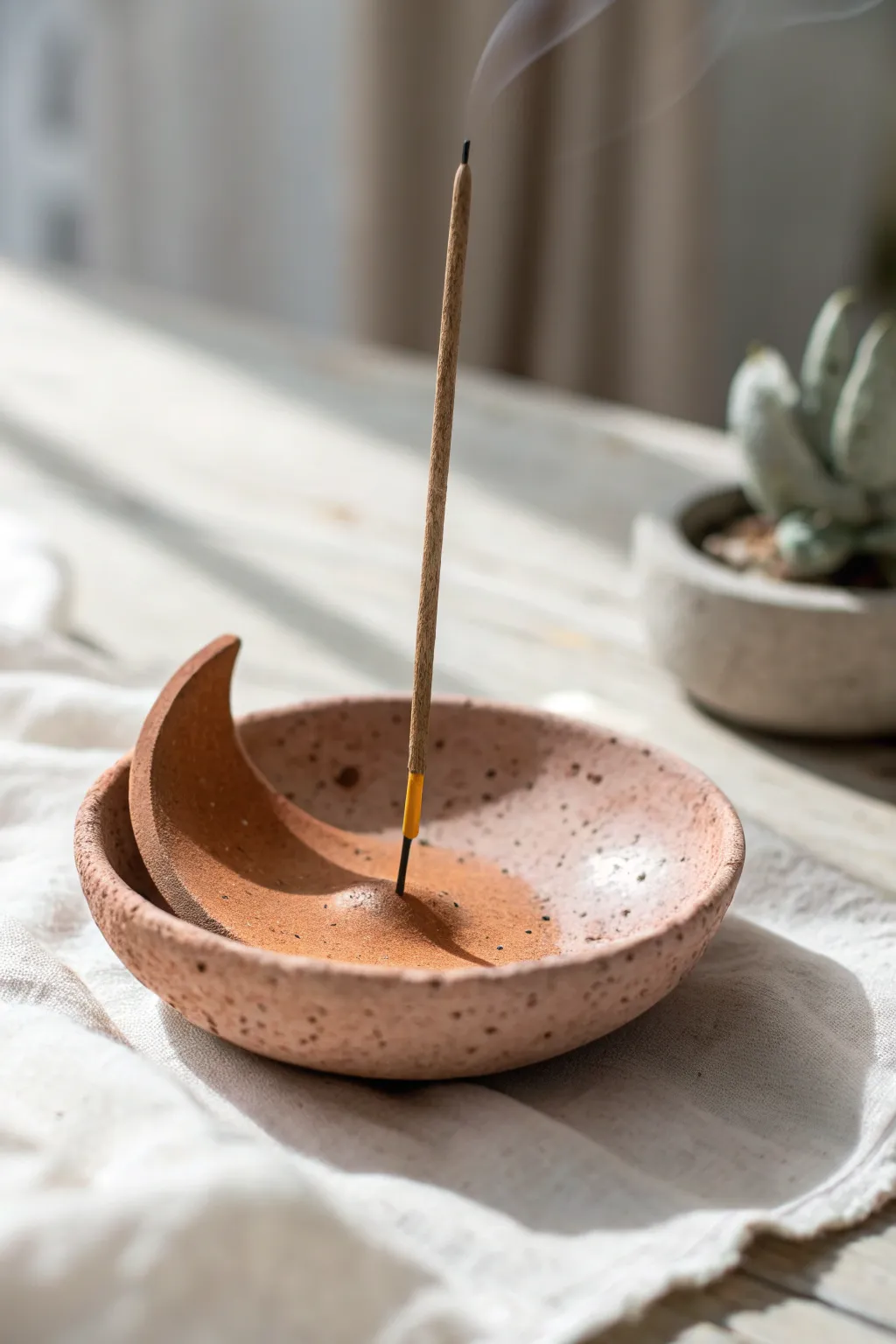 A simple curved clay incense holder with a single stick, calm minimalist styling and warm contrast.