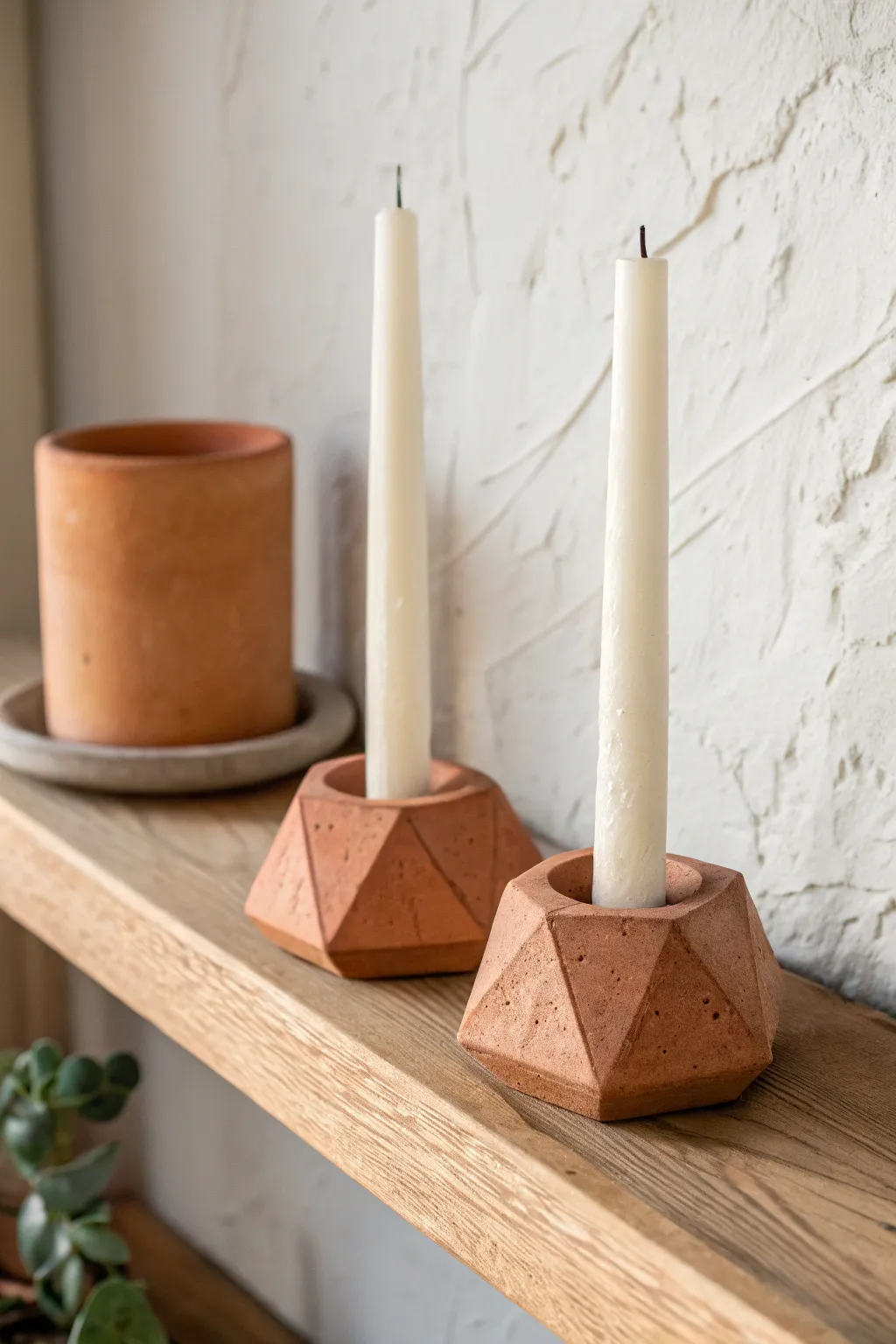 Modern terracotta taper holders with creamy candles, minimalist shelf styling and warm glow.