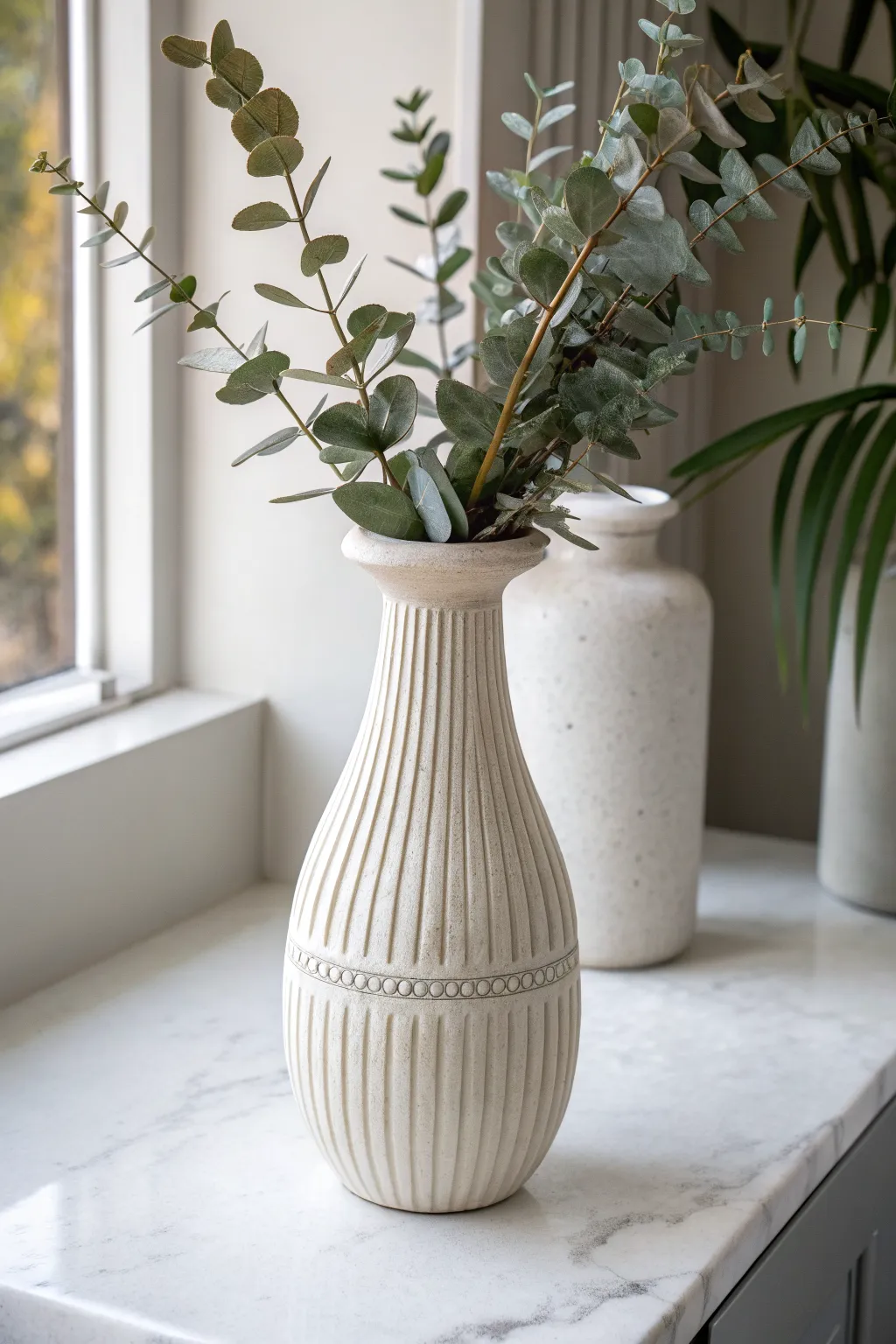 Slim hand-carved air dry clay vase with vertical grooves, styled simply with eucalyptus stems