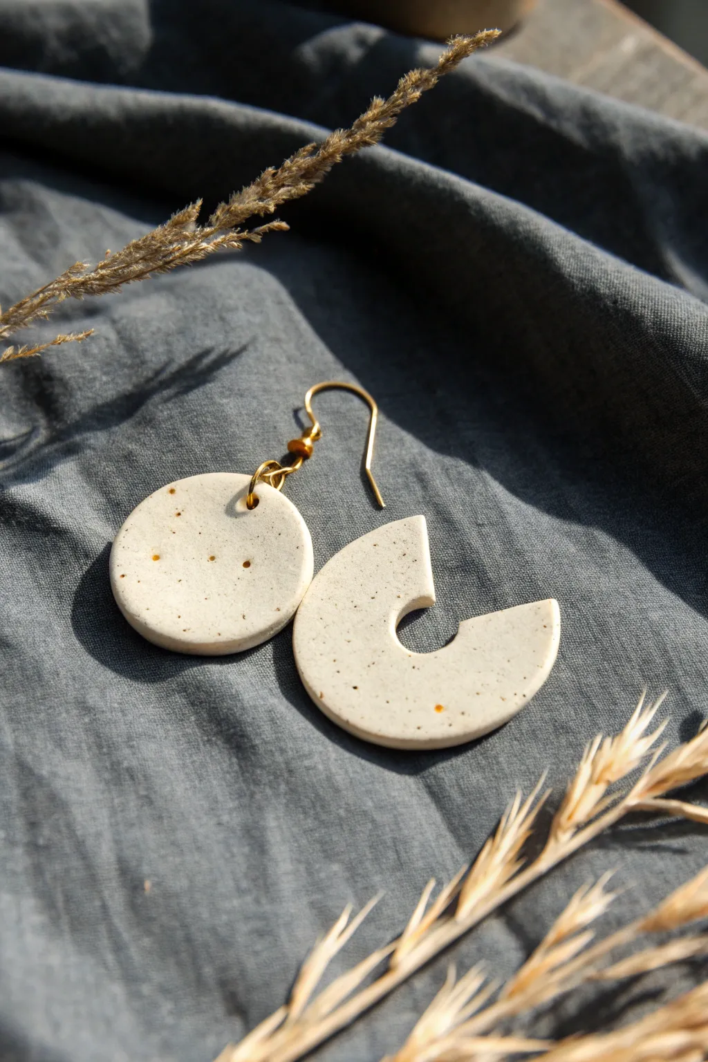 Minimal ceramic earring with playful cutouts, photographed on dark linen for bold contrast