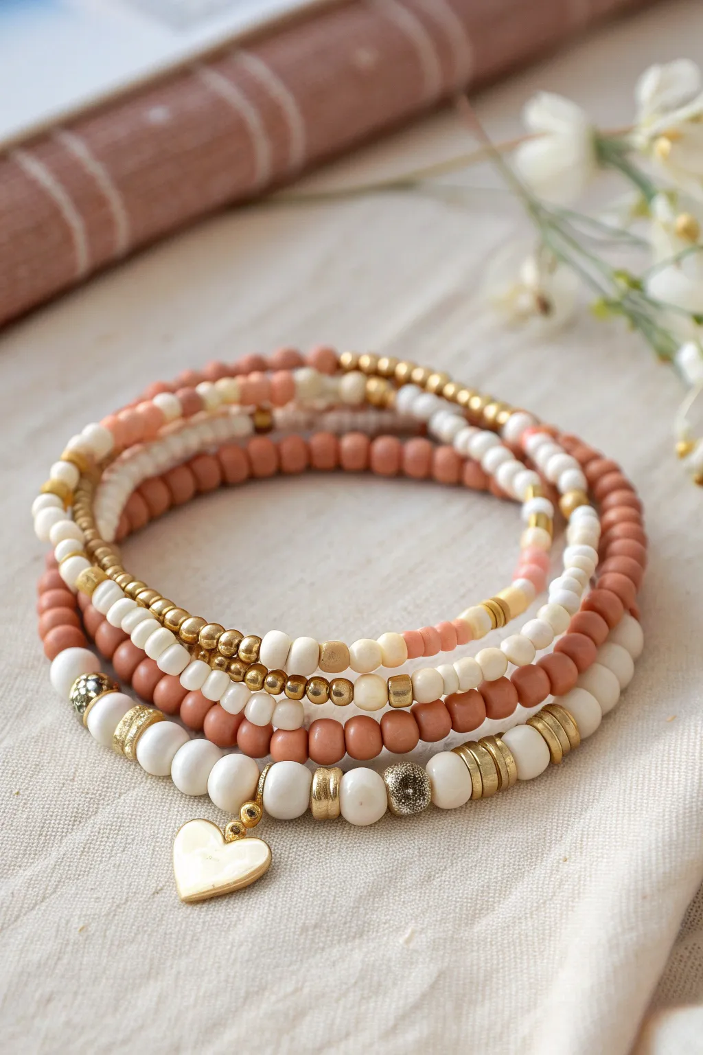 Alternating letter and heart clay beads in soft neutrals, styled as a clean bracelet recipe bundle